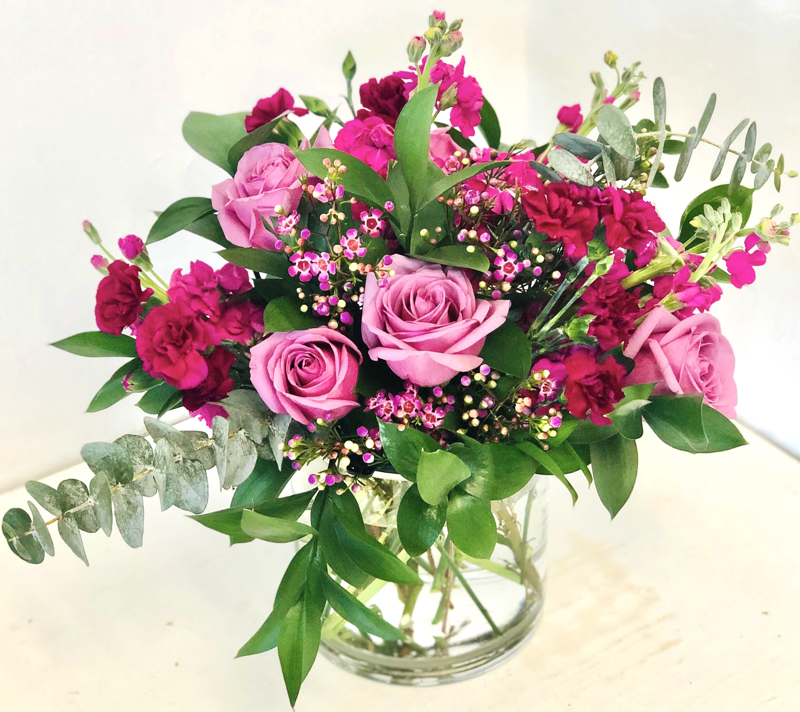 Pink roses and magenta carnations in a clear glass vase