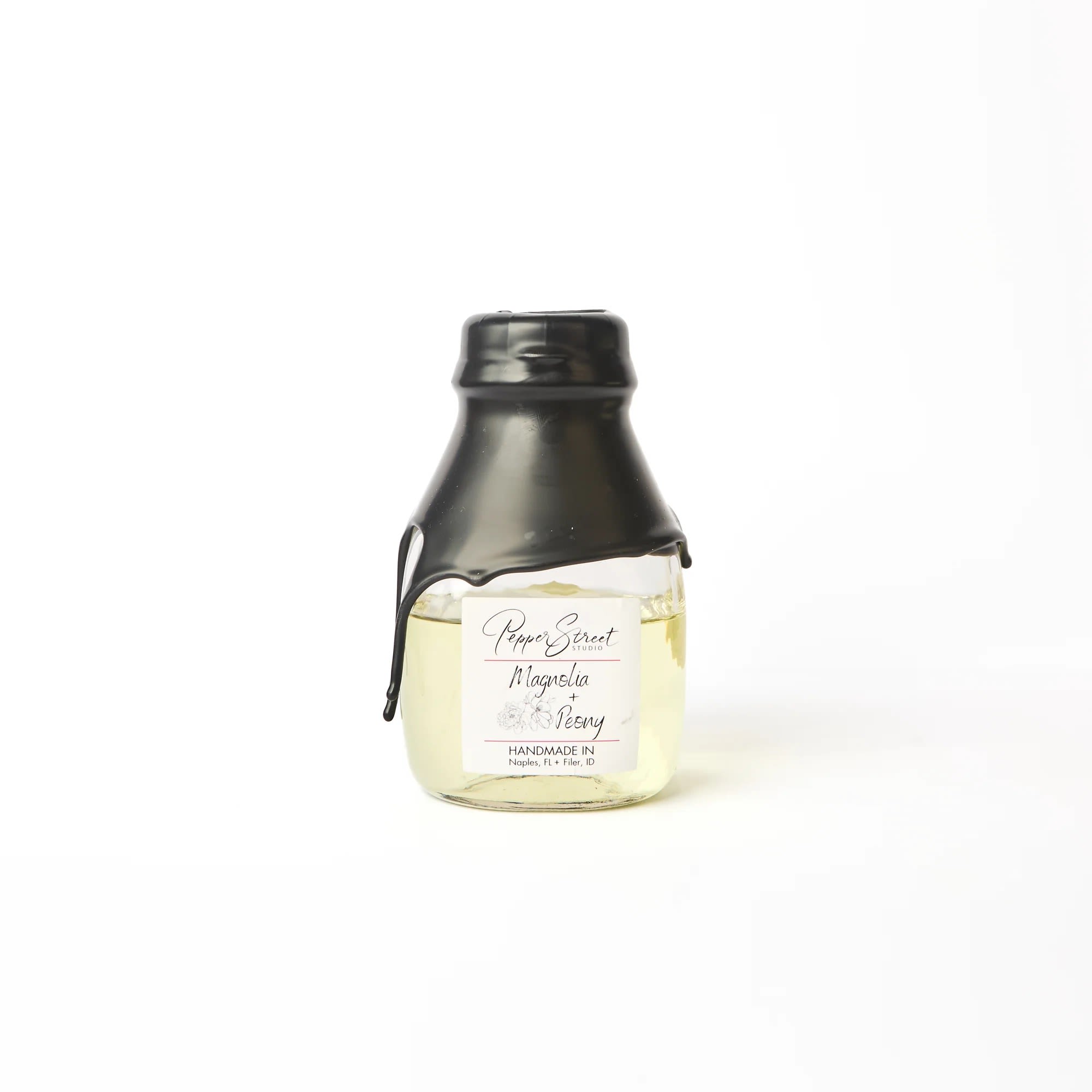 MAGNOLIA + PEONY LARGE ROOM DIFFUSER - Pepper Street's signature black wax hand-dipped room diffuser is in a short milk glass bottle. It includes ten bamboo reeds and a wood flower for a sweet touch and effective scent diffusion. The best part? Their diffuser oils are wholly toxin-free and contain no additional alcohol, ensuring a long-lasting scent that will last you longer than a year. A pull tab on the back allows easy access to the lid. Weight: 9 fl oz | 266 ml Magnolia + Peony Immerse yourself in the refreshing scent of a blossoming spring garden with this exquisite blend of floral fragrances. The crisp and breezy magnolia notes are perfectly balanced with a hint of sweetness from the peony, creating a delicate aroma that's sure to revitalize and calm any space in your home. Whether you have a love for all things floral or simply want to add a touch of tranquility to your living space, this fragrance is guaranteed to delight. Linen gift bag included.