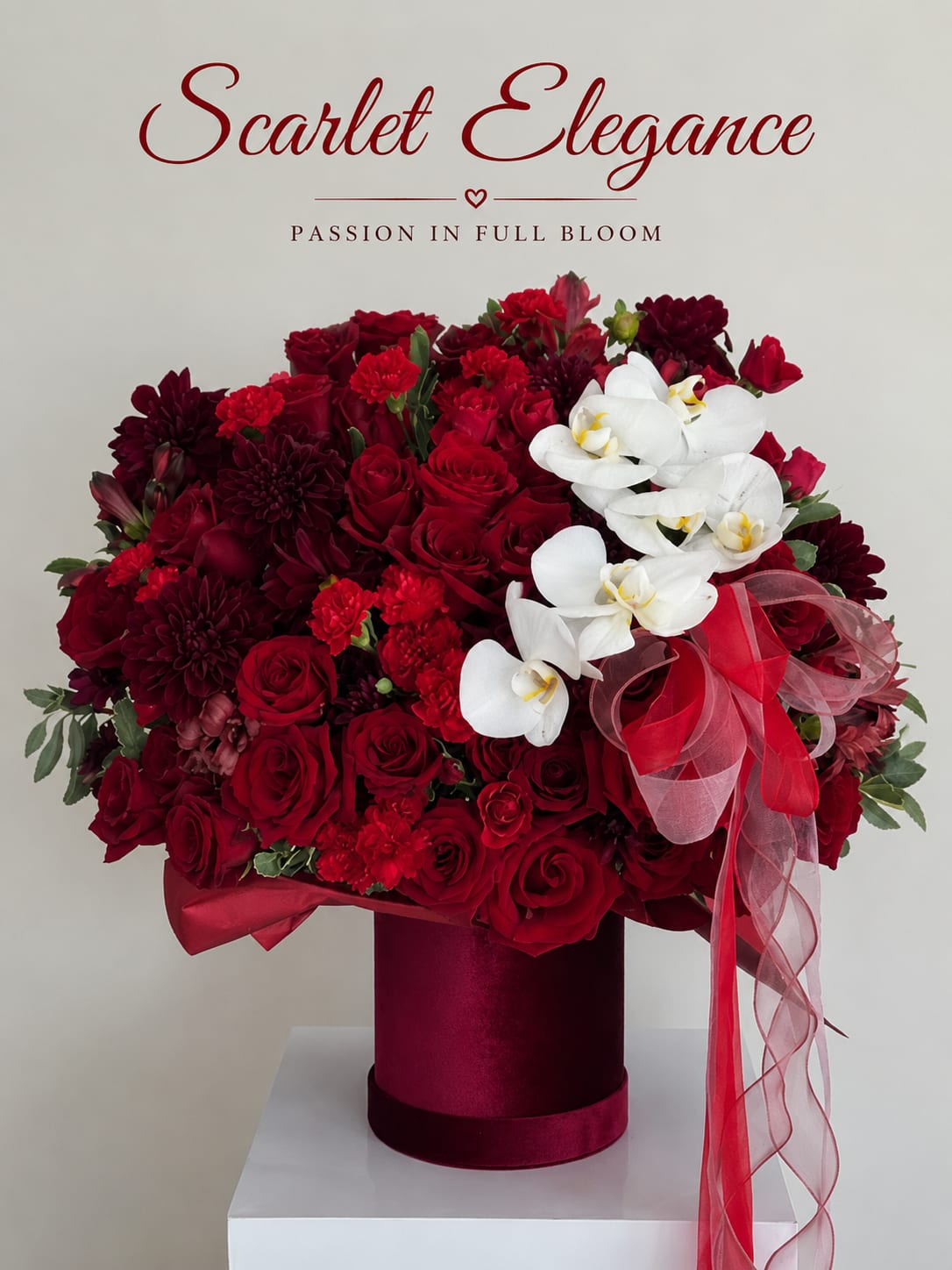 Red rose and orchid arrangement in a burgundy hat box with ribbon