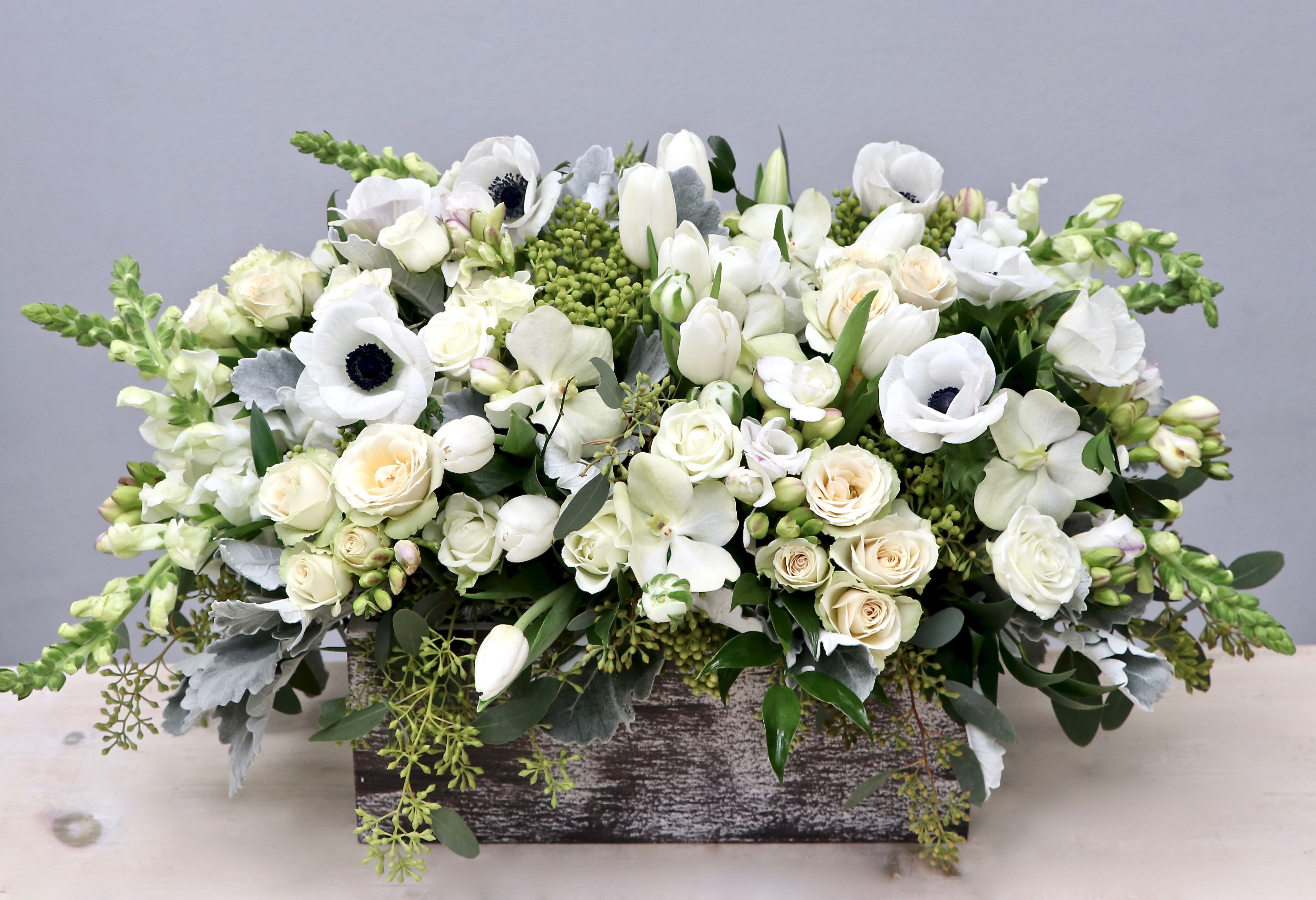 Low arrangement of white and cream flowers in a rustic wooden box