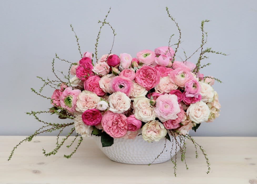 Low arrangement of pink and white roses and ranunculus in a white textured bowl