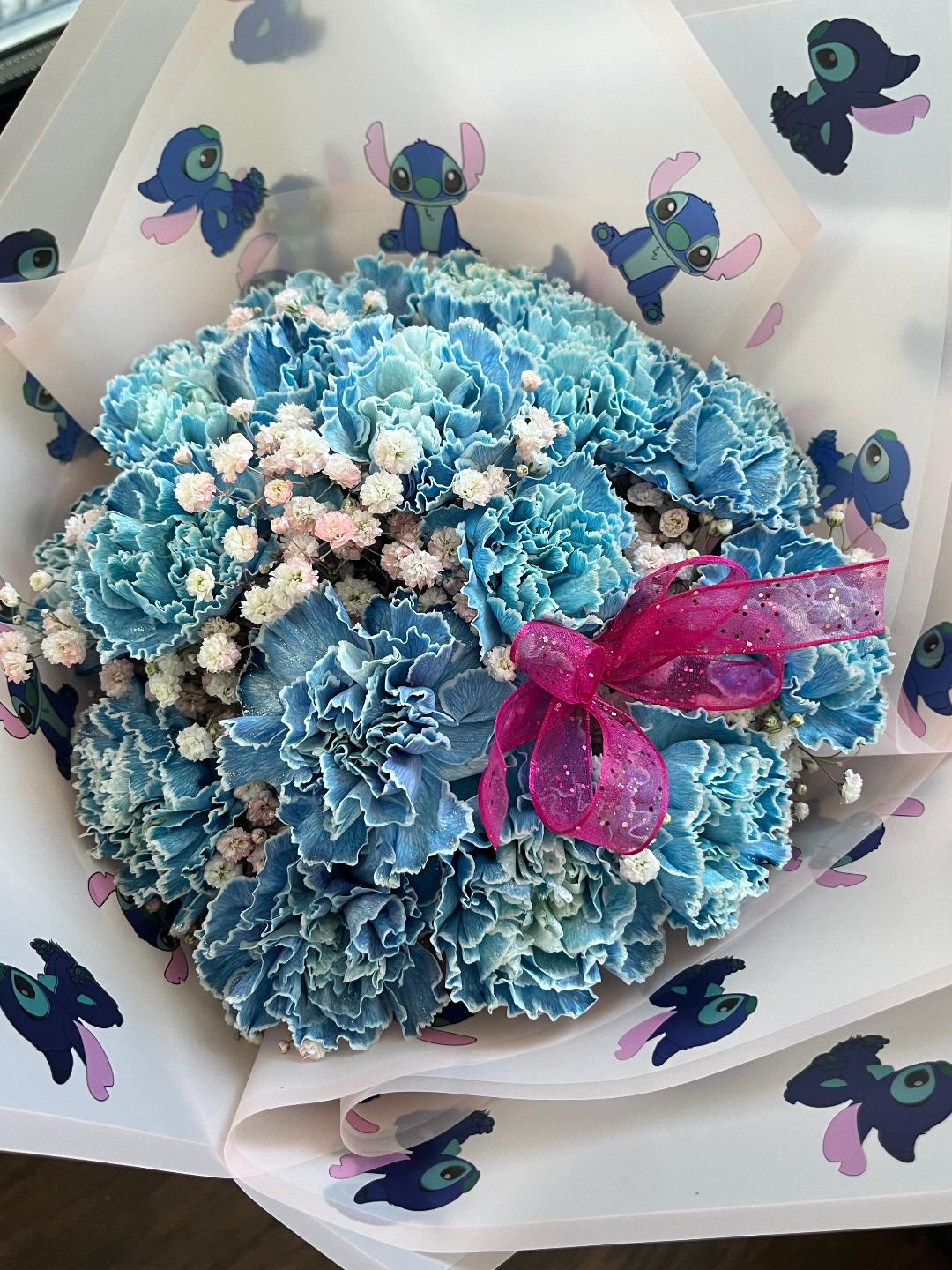 Blue carnation bouquet with baby's breath and a pink ribbon