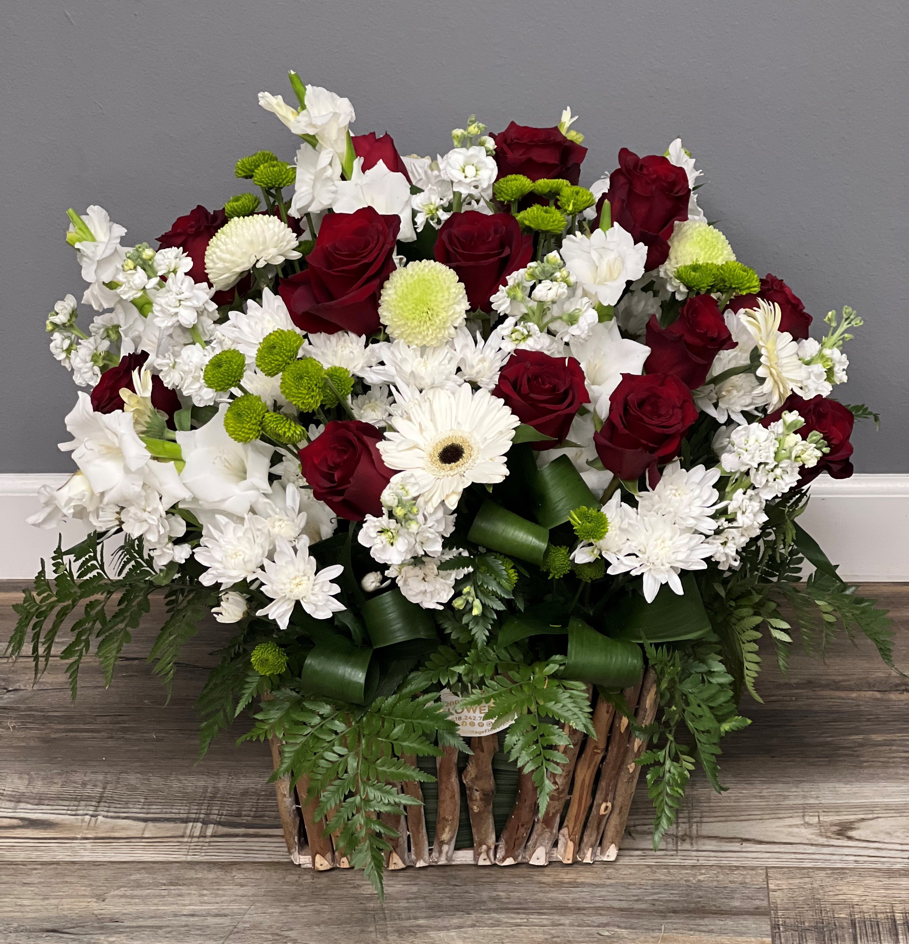 Red roses and white flowers in a rustic basket arrangement