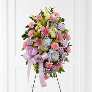 Blessings Of The Earth Spray - The FTD® Blessings of the Earth™ Easel is a soft and serene arrangement that elegantly honors the life of the deceased. Lavender roses, pink carnations, pink Asiatic lilies, blue hydrangea, yellow stock, lavender button poms, solidago and lush greens are beautifully accented with a lavender satin ribbon and displayed on a wire easel to create a gorgeous display for their memorial service. 