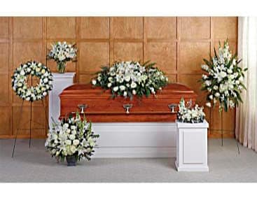 White floral funeral arrangements around a casket