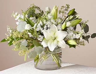 White lilies and green buds in a clear glass vase