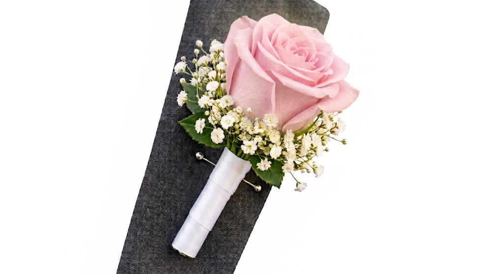 Pink rose boutonniere with white baby's breath on a dark jacket
