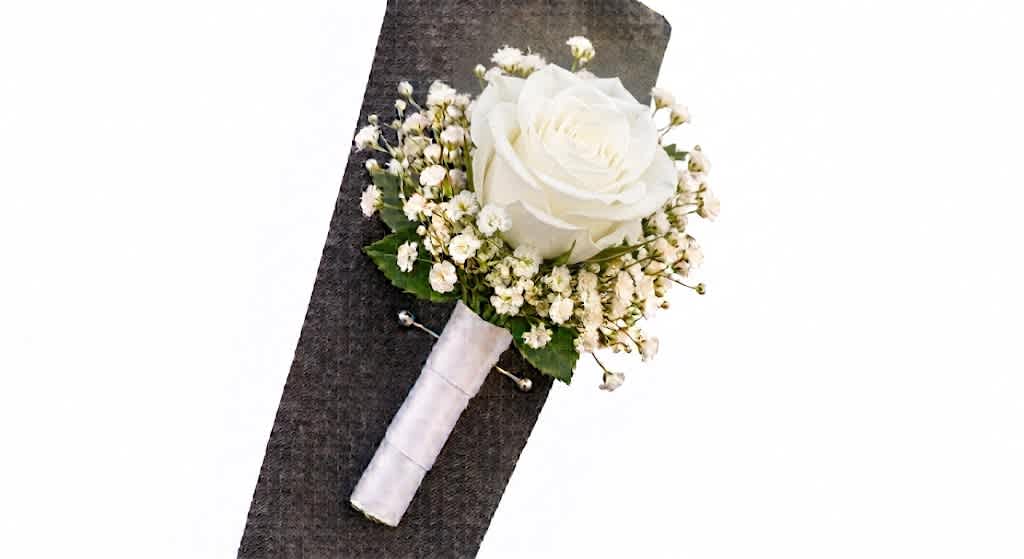 White rose boutonniere with baby's breath on a dark suit lapel