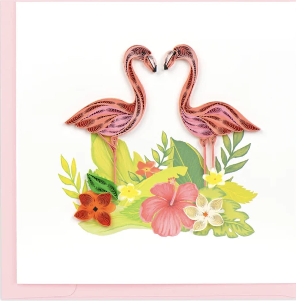 Two pink flamingos above tropical flowers and leaves on a white card