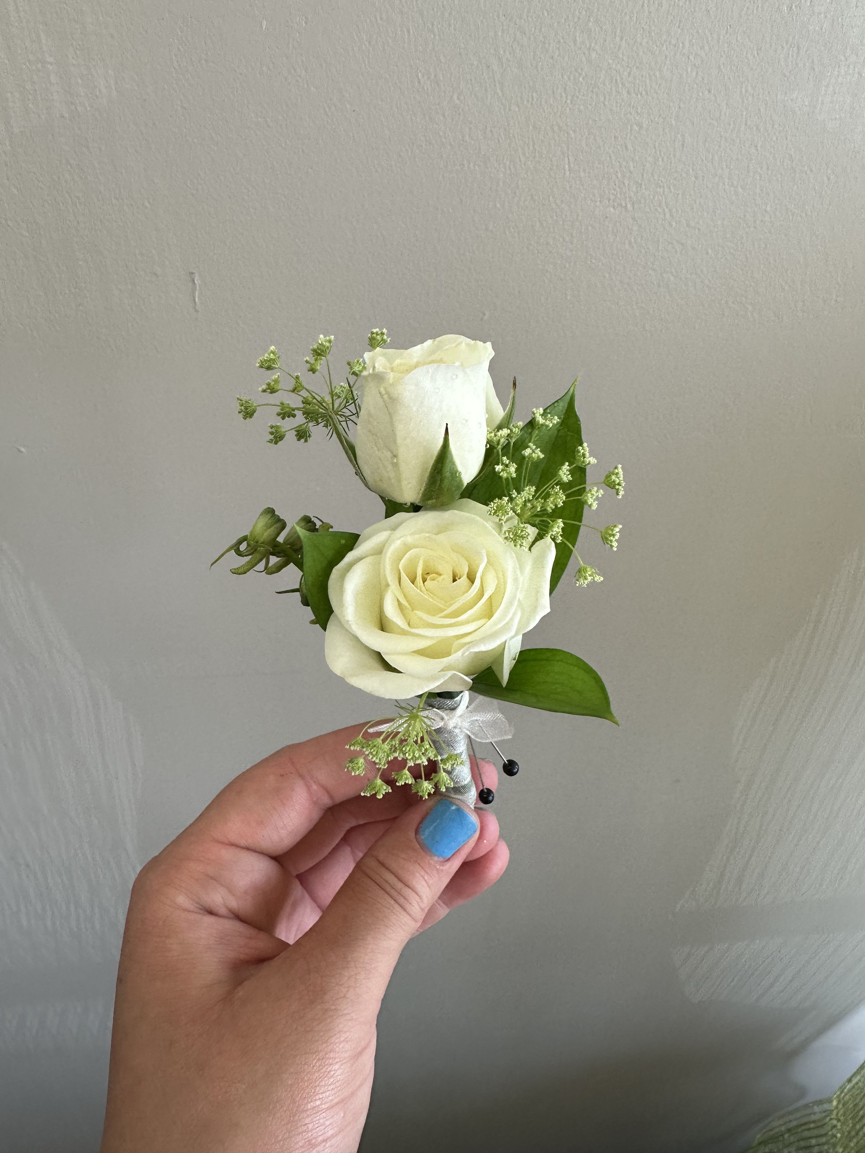 Small white rose boutonniere with greenery and ribbon