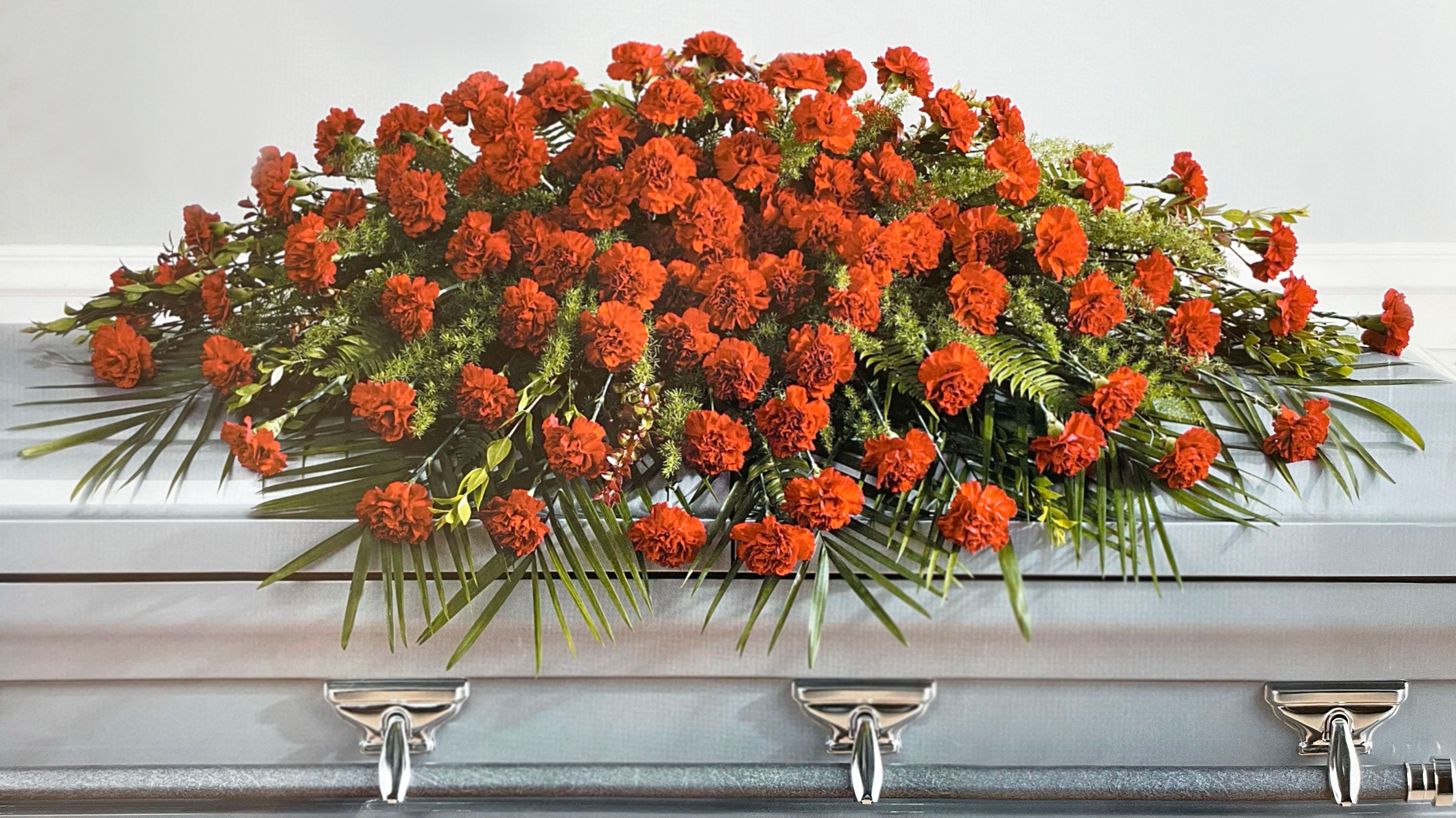 Orange carnation casket spray with palm fronds