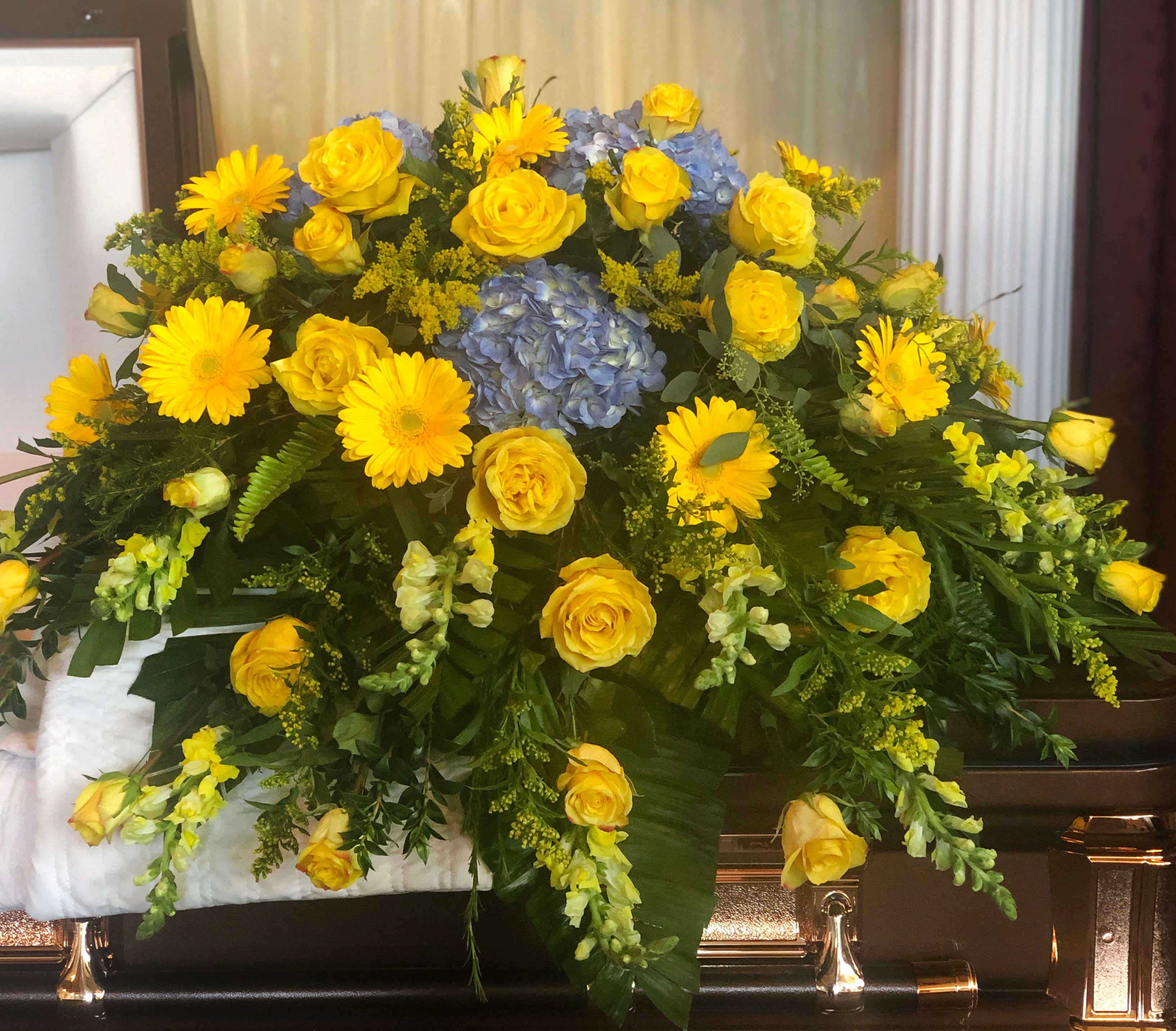 Yellow roses and daisies with blue hydrangea in a casket spray