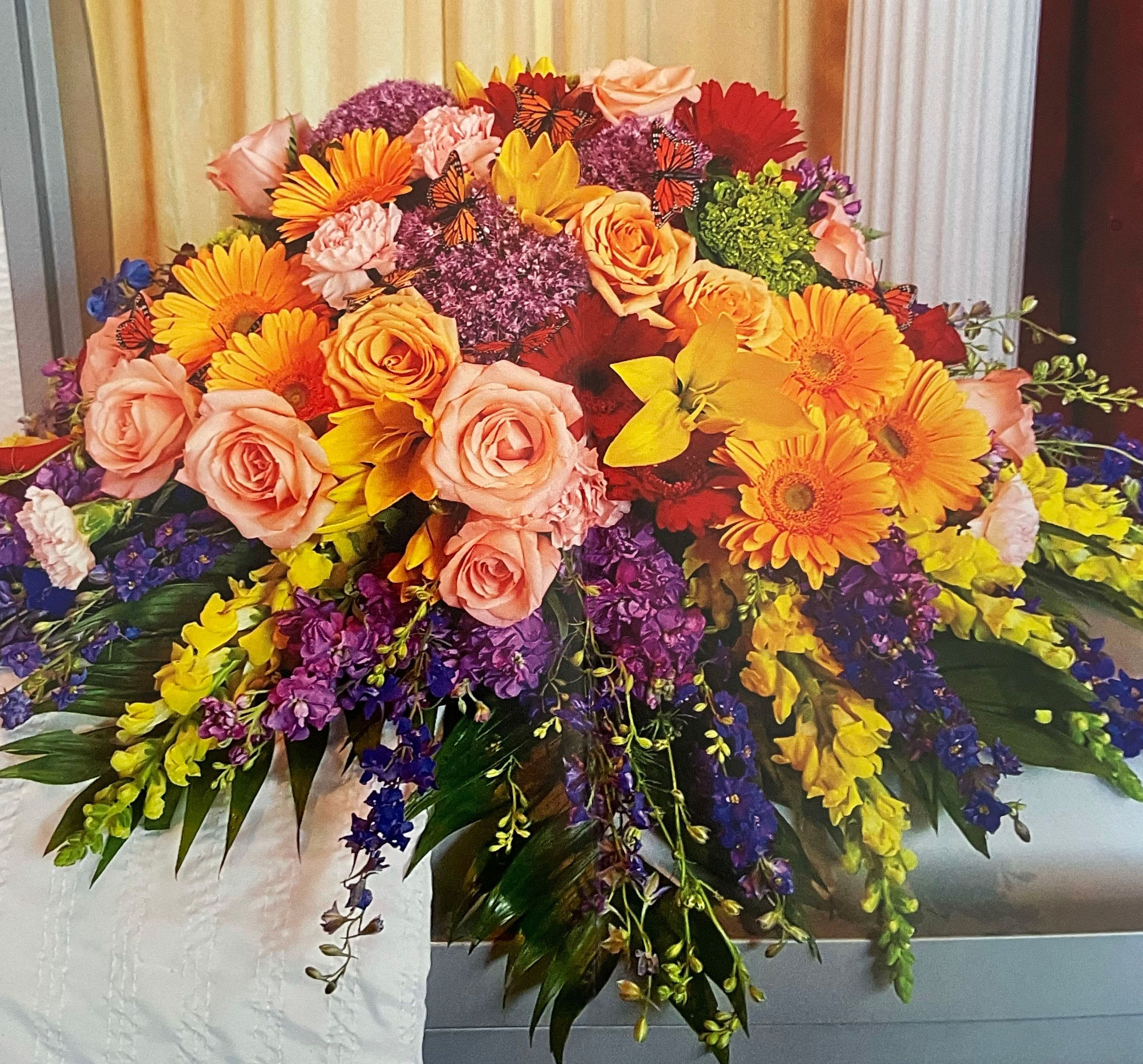 Large colorful floral arrangement with roses, gerbera daisies, and purple blooms