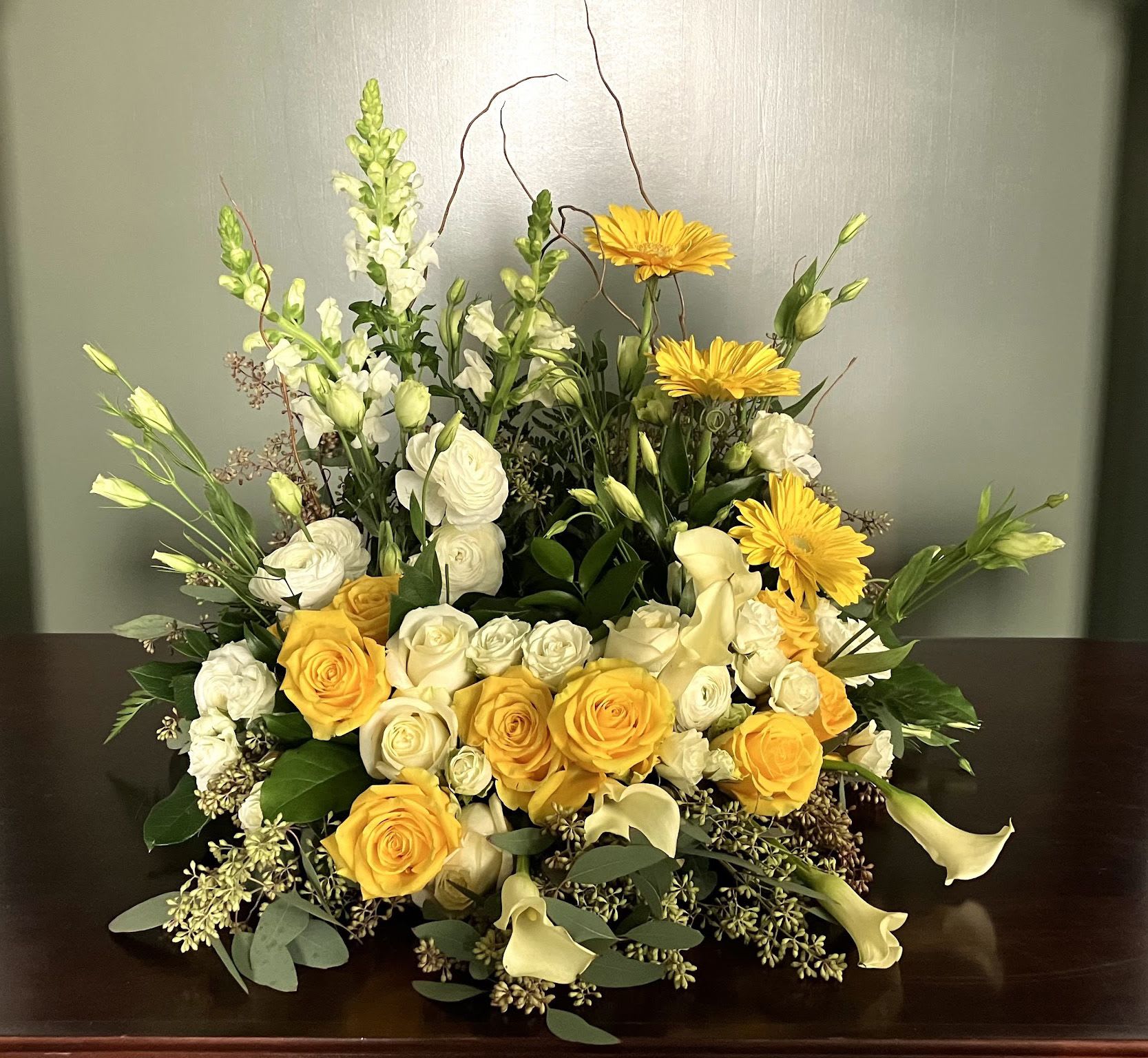 Yellow and white floral arrangement with roses, calla lilies, and daisies