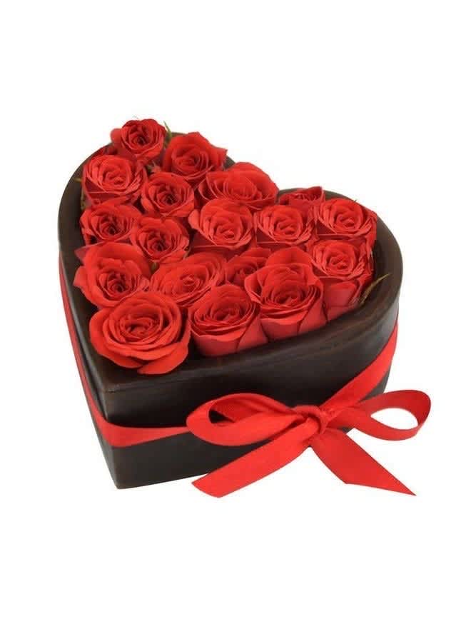 Heart-shaped box filled with red roses and tied with a red ribbon