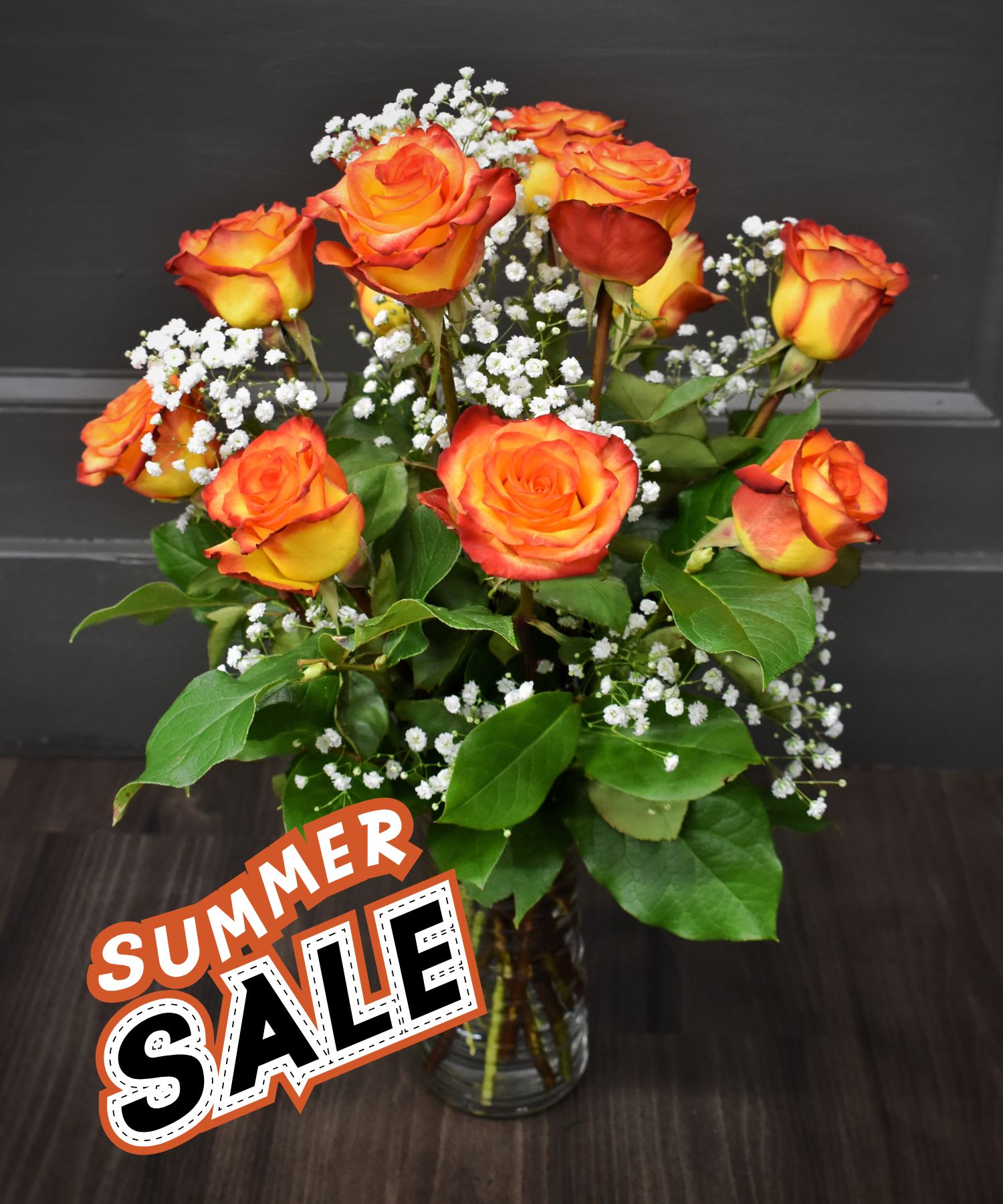 Orange and yellow roses in a glass vase with white filler flowers
