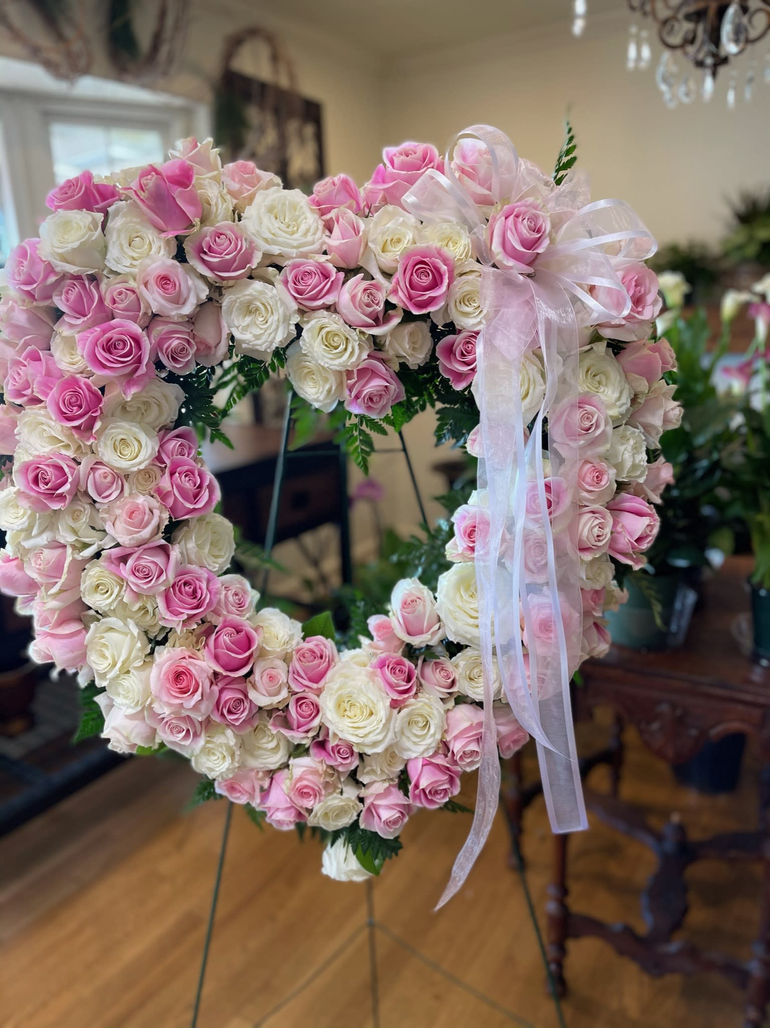 Heart-shaped arrangement of pink and white roses with a sheer ribbon