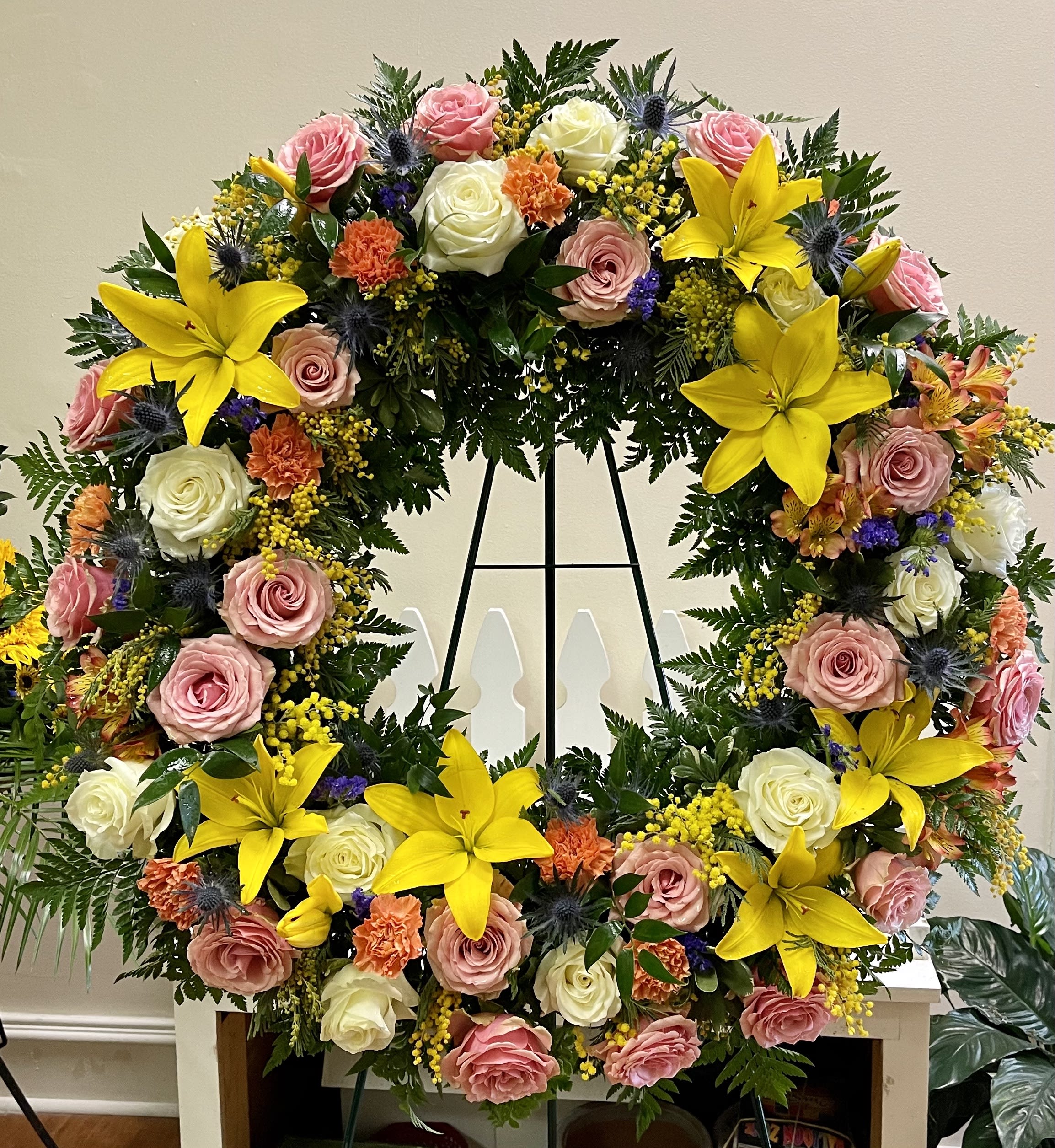 Large floral wreath with pink and white roses and bright yellow lilies