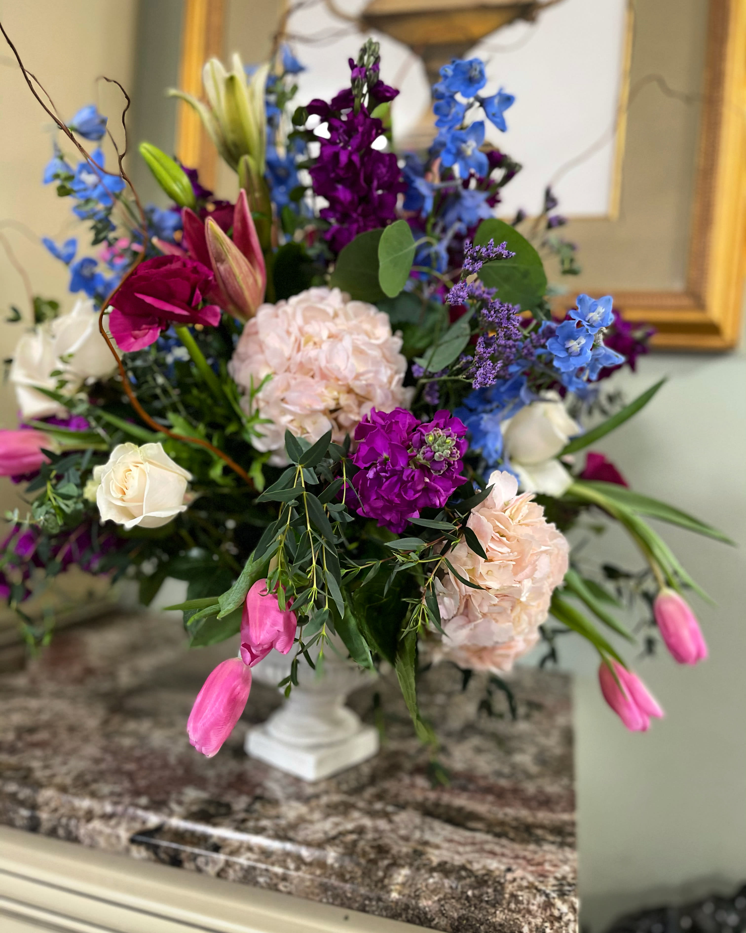 Colorful mixed flower arrangement in a white pedestal vase