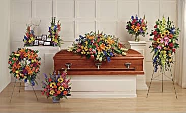 Colorful floral funeral casket spray with standing wreaths and arrangements