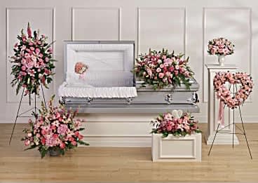 Pink floral funeral casket spray with matching standing arrangements