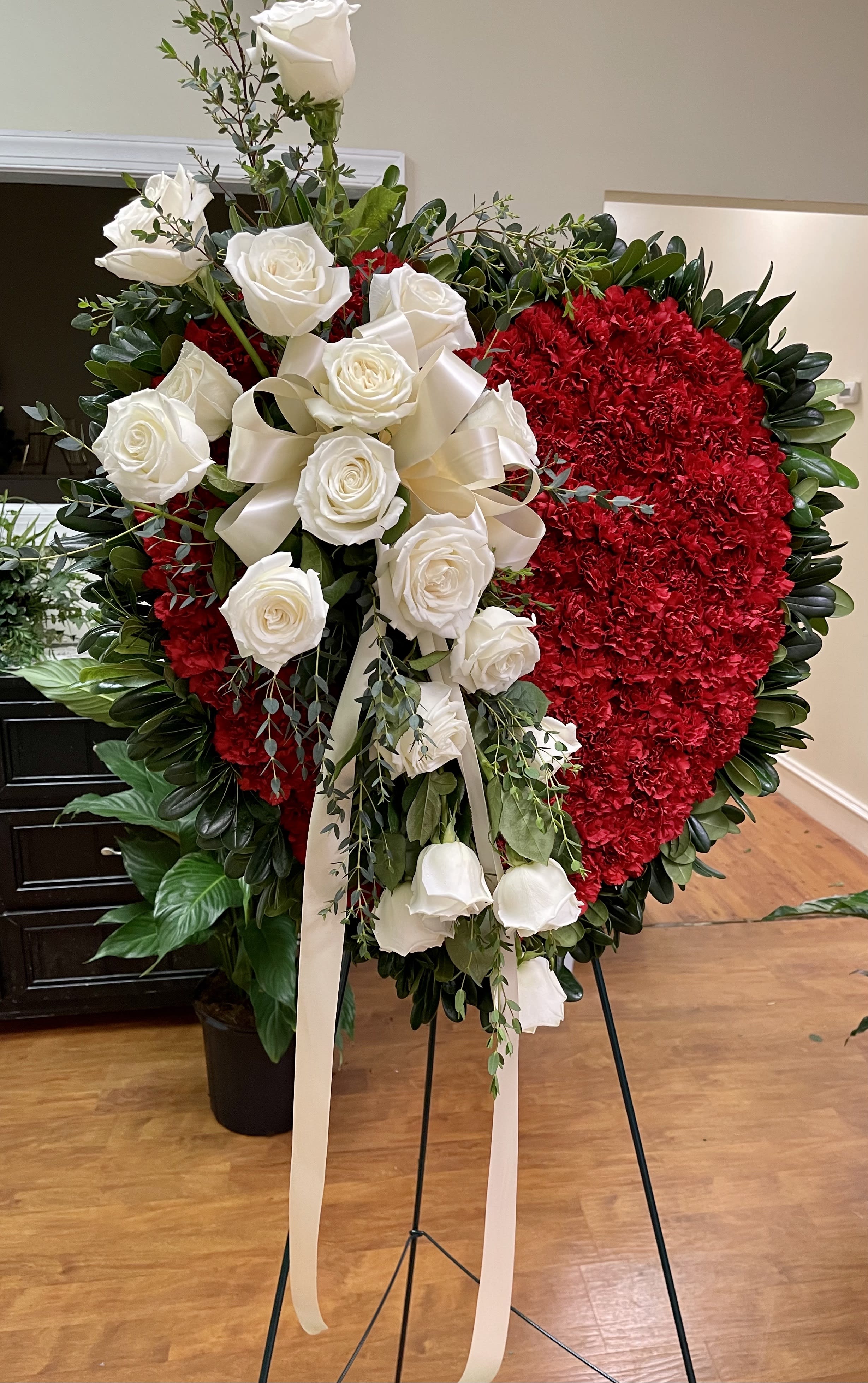 Heart-shaped red floral wreath with white roses and ribbon