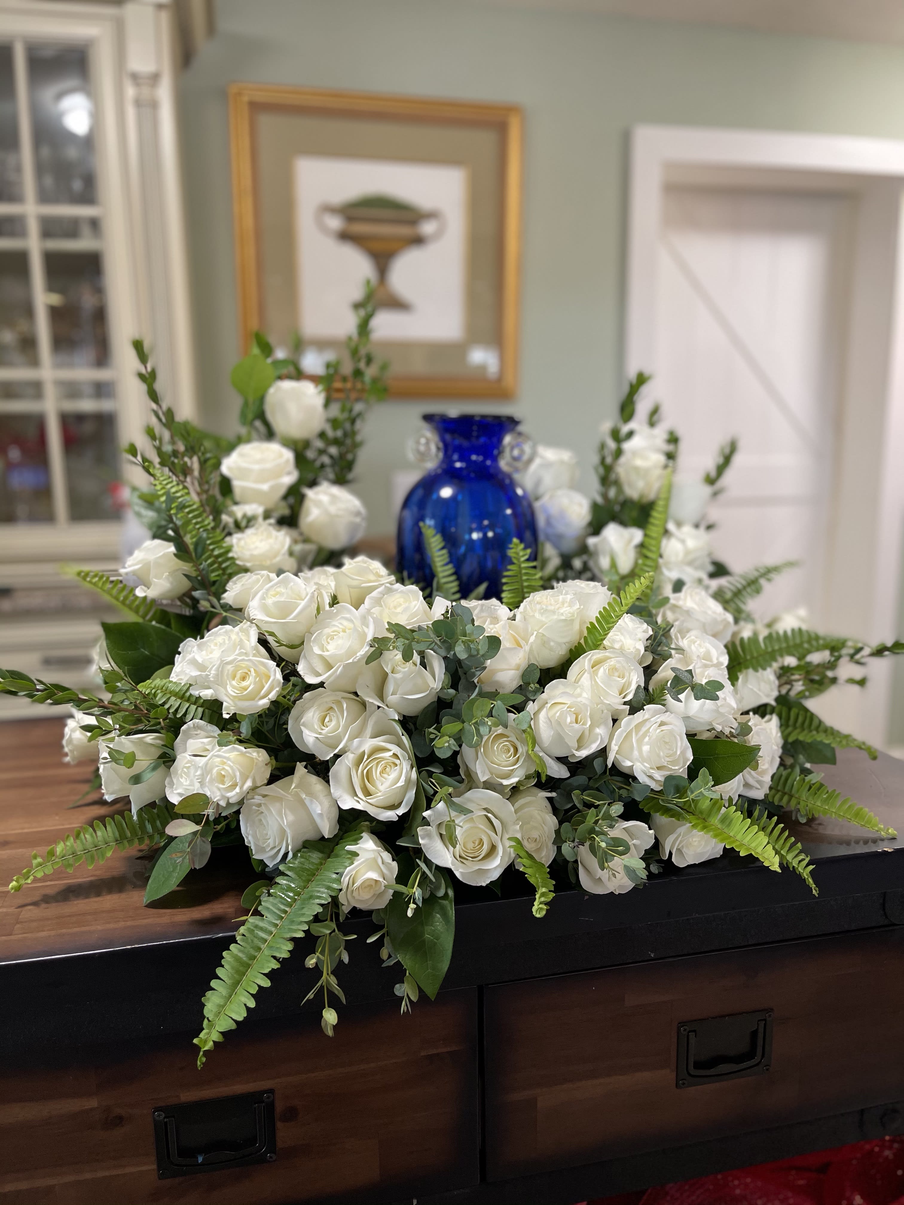 White rose arrangement with ferns and eucalyptus on a table