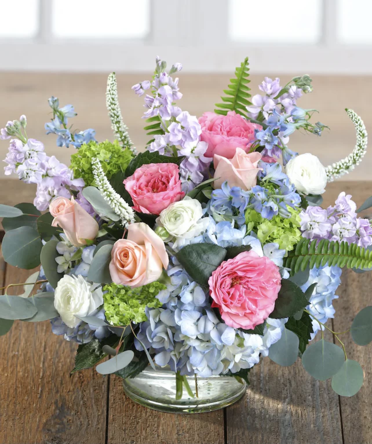 Pastel floral arrangement in a clear glass vase with roses and hydrangeas