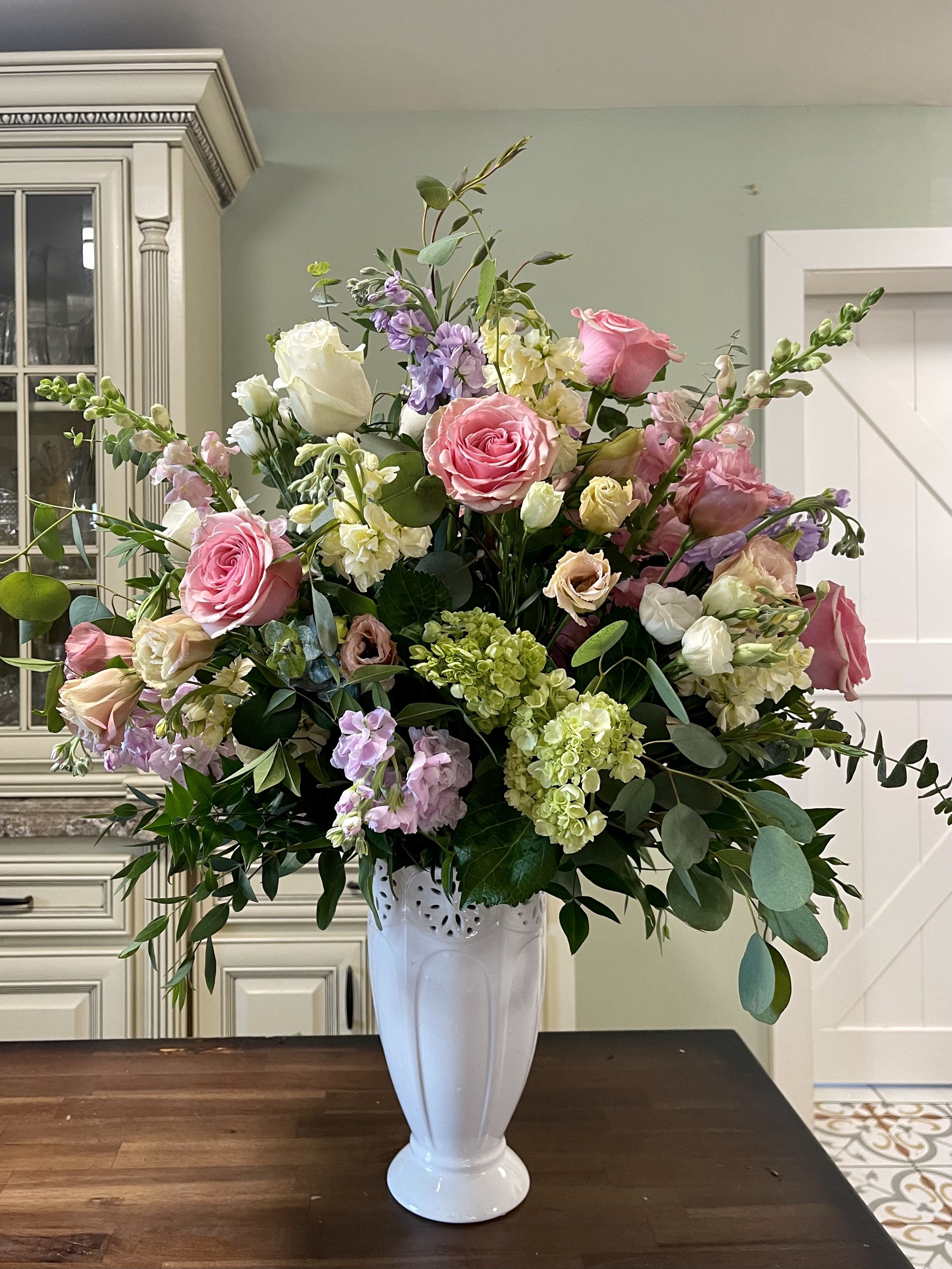 Large pink and white floral arrangement in a white vase