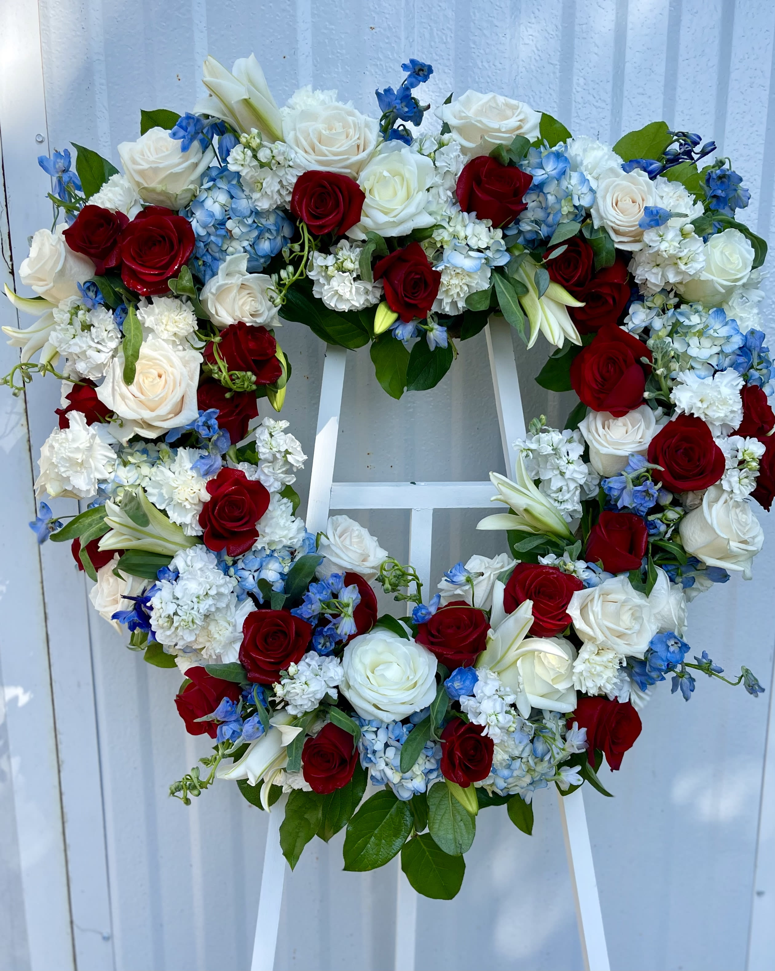 Heart-shaped floral wreath with red and white roses and blue flowers