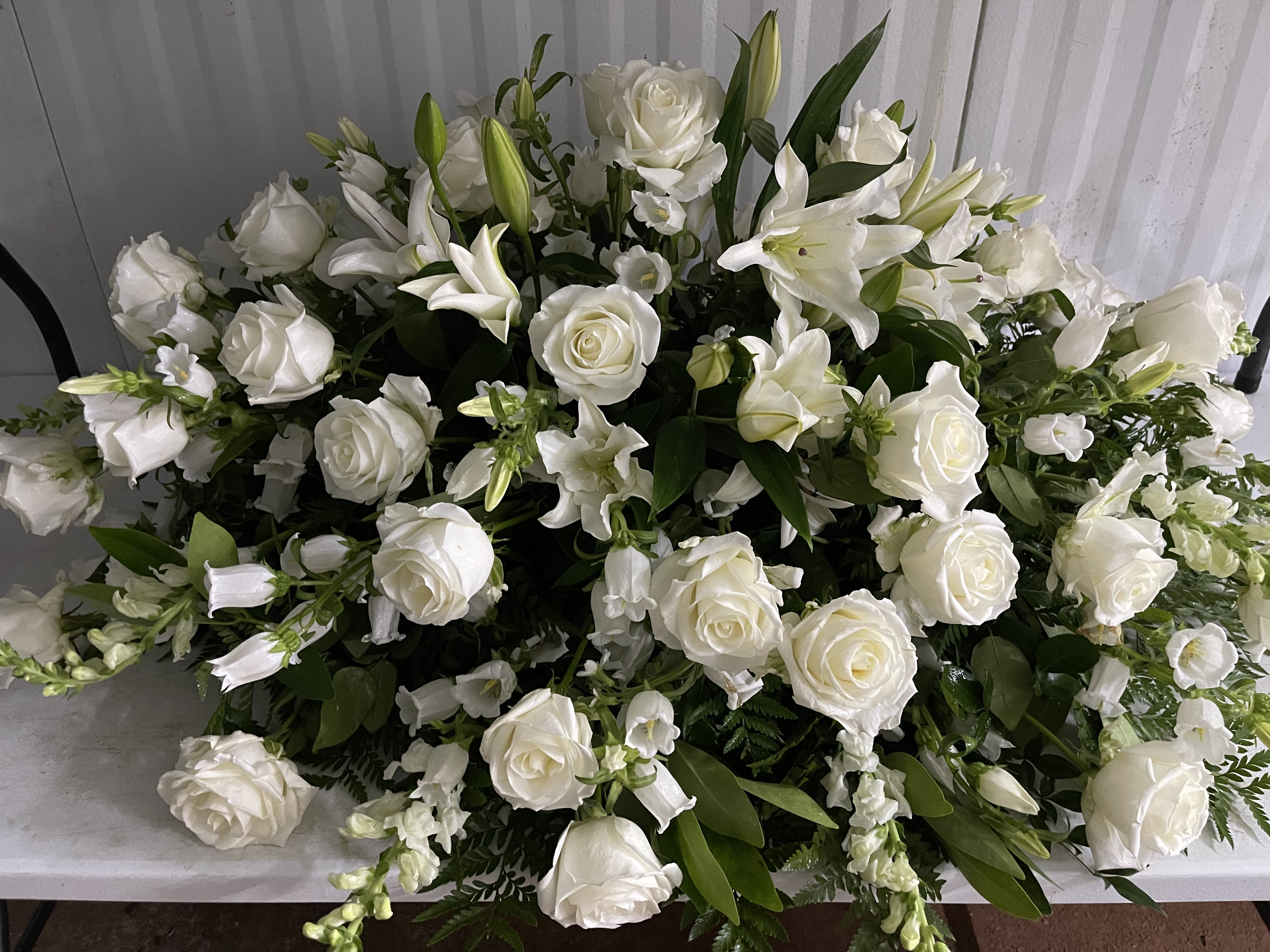 Large white floral arrangement with roses and lilies