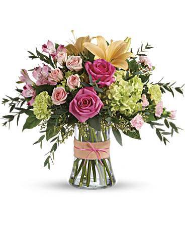 Bouquet of pink roses, lilies, and green hydrangeas in a glass vase