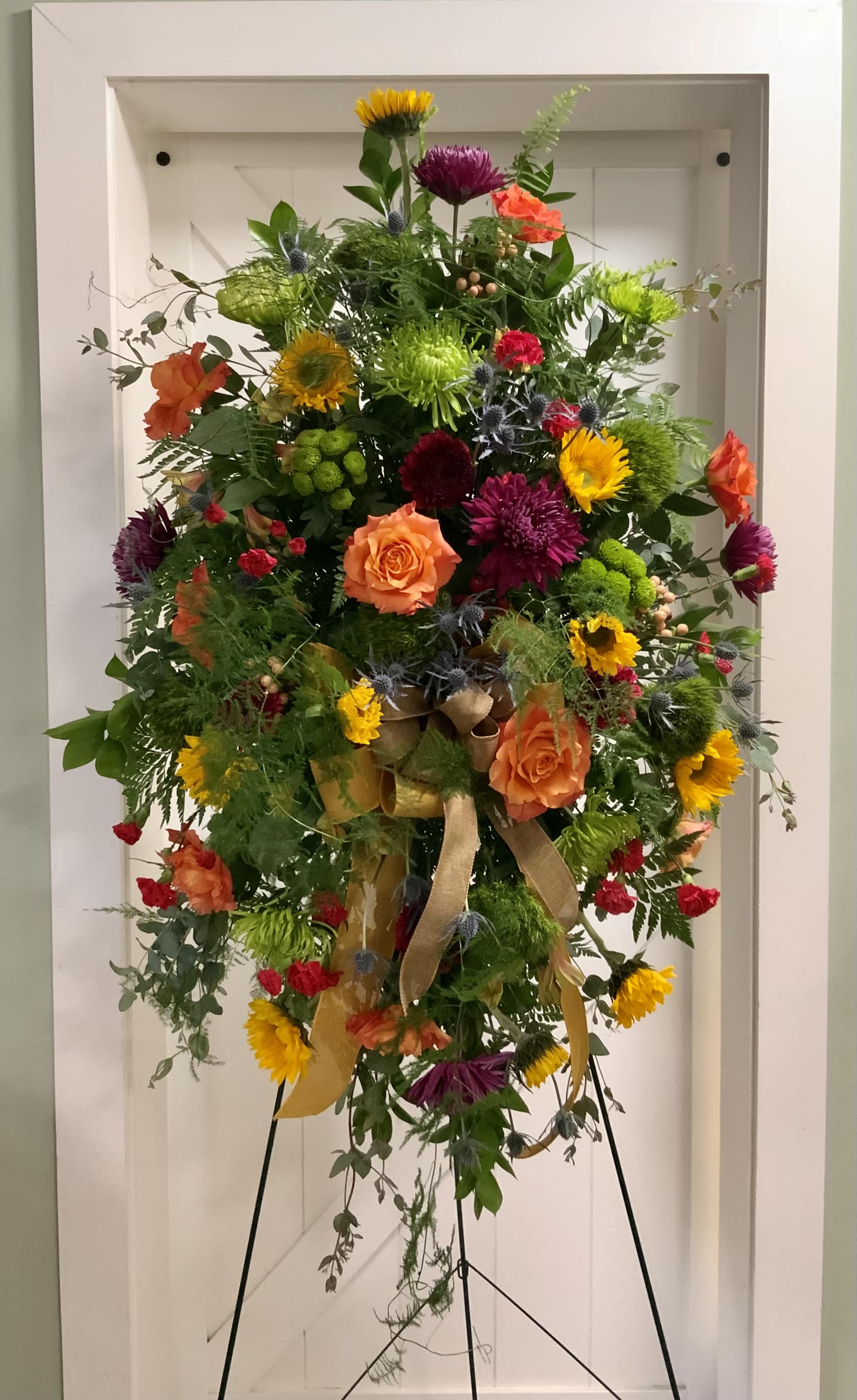 Tall colorful floral standing spray with ribbon on an easel