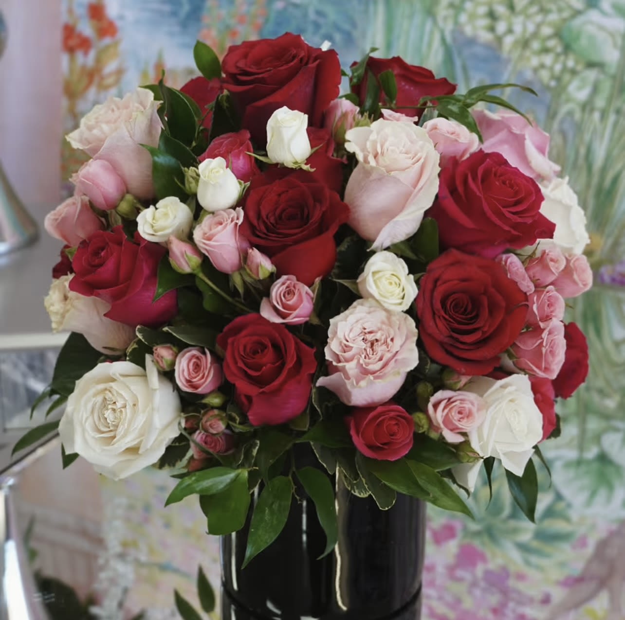 Bouquet of red, pink, and white roses in a black vase