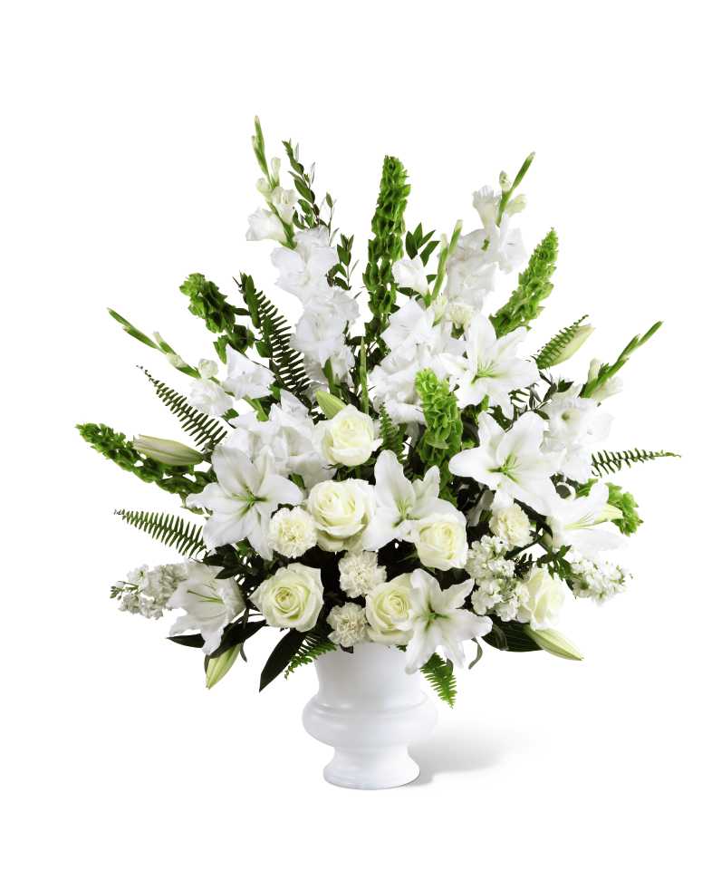  Morning Stars Arrangement - The FTD Morning Stars Arrangement is a brilliant expression of peace and soft serenity. White roses, carnations, gladiolus, stock, and Oriental lilies are accented with the bright green stems of Bells of Ireland and a gorgeous assortment of lush greens, while seated in a white designer plastic urn to create a beautiful way to honor the life of the deceased.