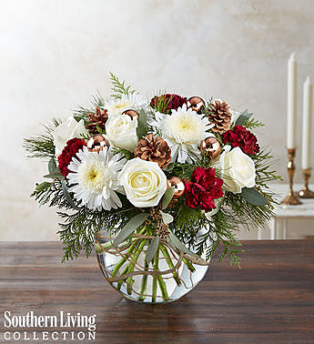 White and red floral arrangement in a clear glass vase with pinecones