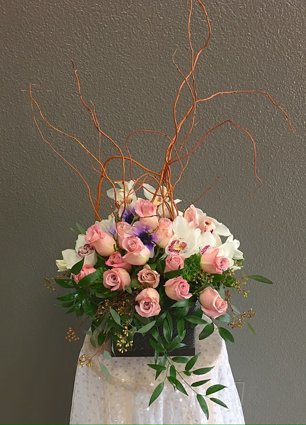 Pink roses and white orchids in a black container with curly branches
