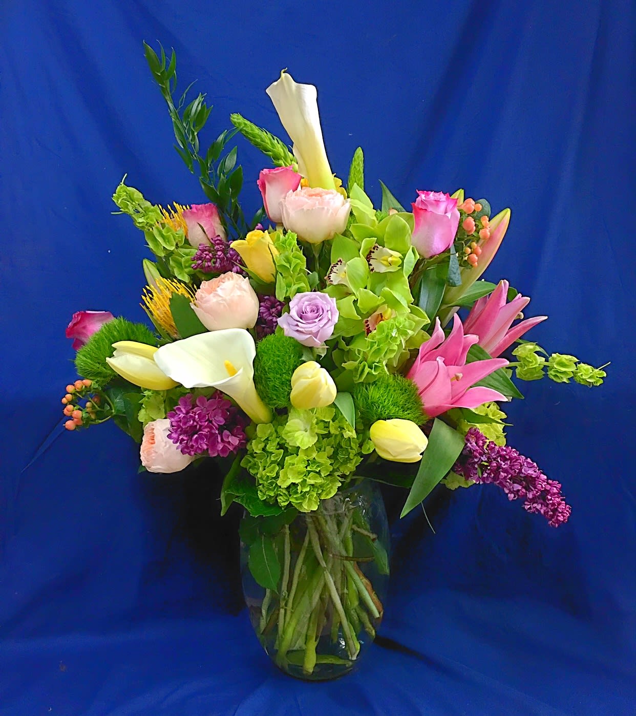 Mixed bouquet with pink roses, calla lilies, and purple flowers in a glass vase