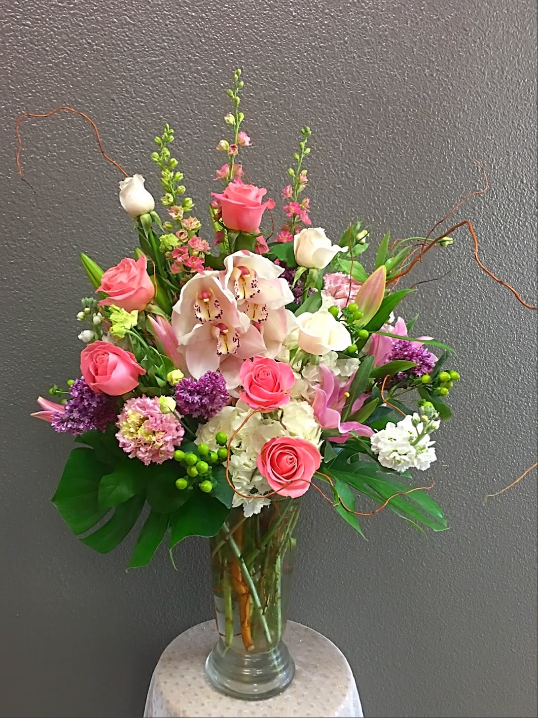 Pink roses and orchids arranged in a clear glass vase