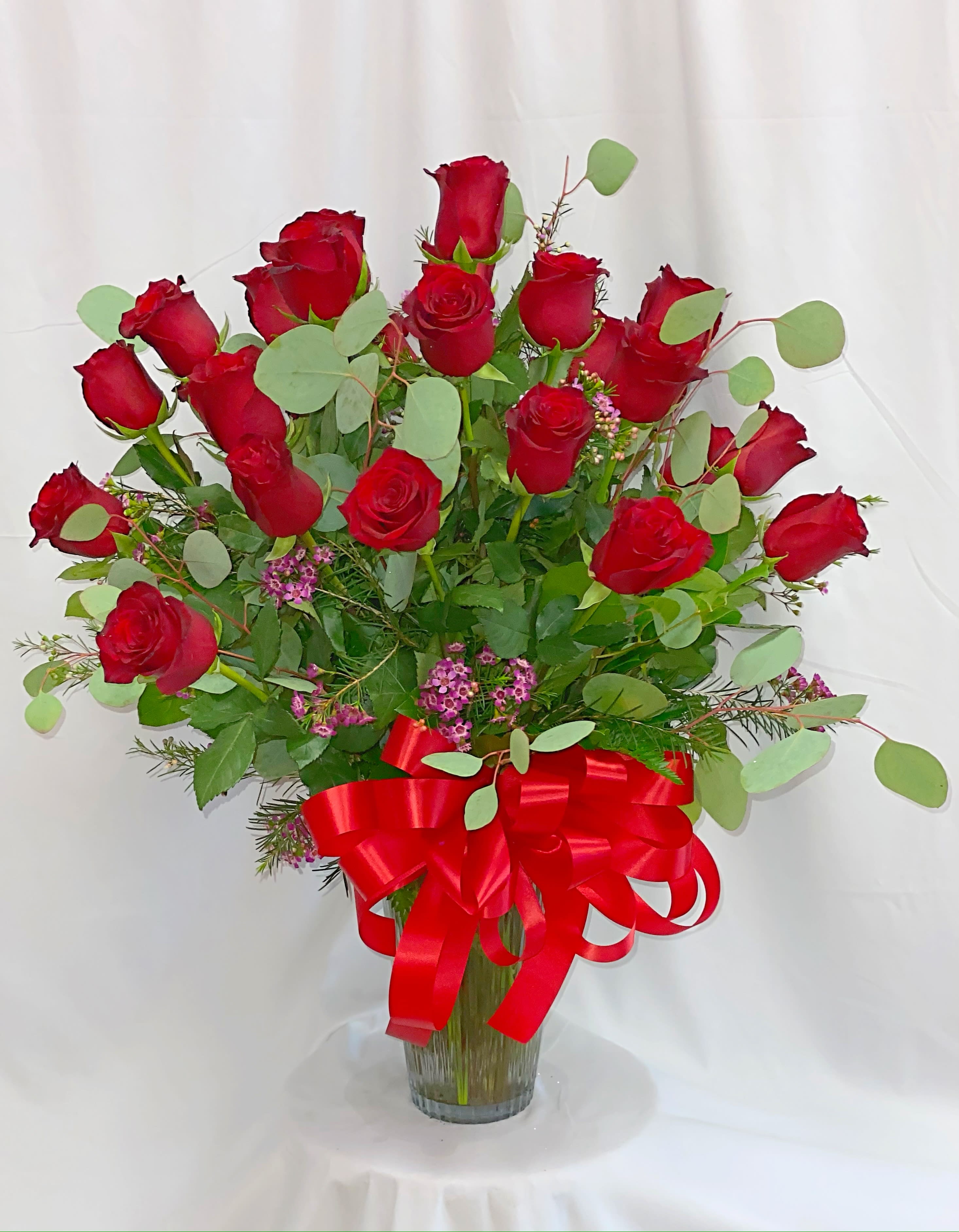 Red roses in a clear glass vase with a red ribbon bow