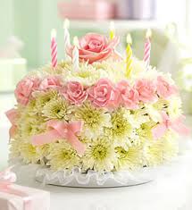 Pink roses and white daisies arranged as a cake with striped candles