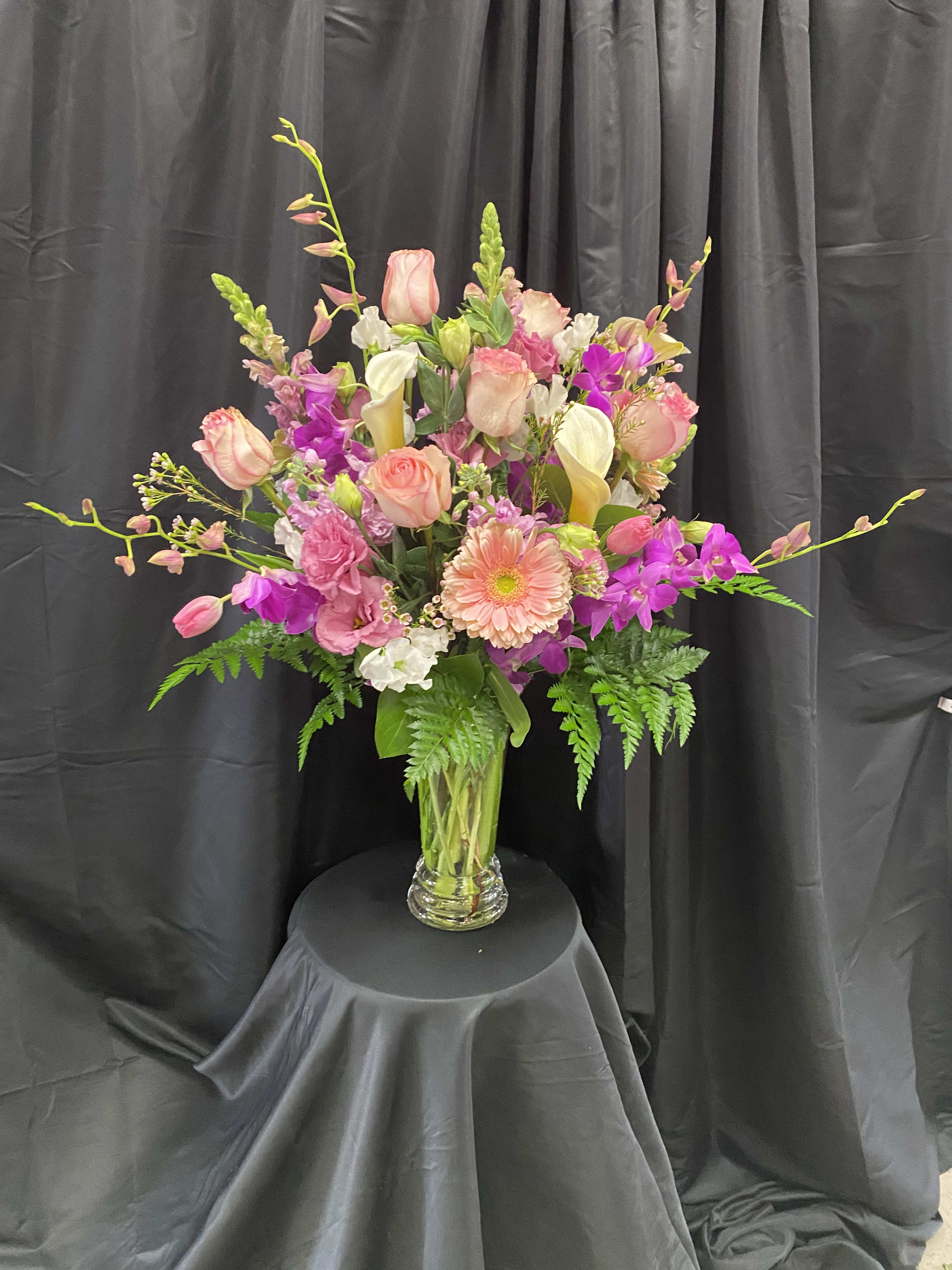 Tall mixed bouquet in a clear glass vase with pink, white, and purple blooms