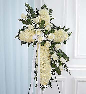White floral standing cross with ribbon on an easel