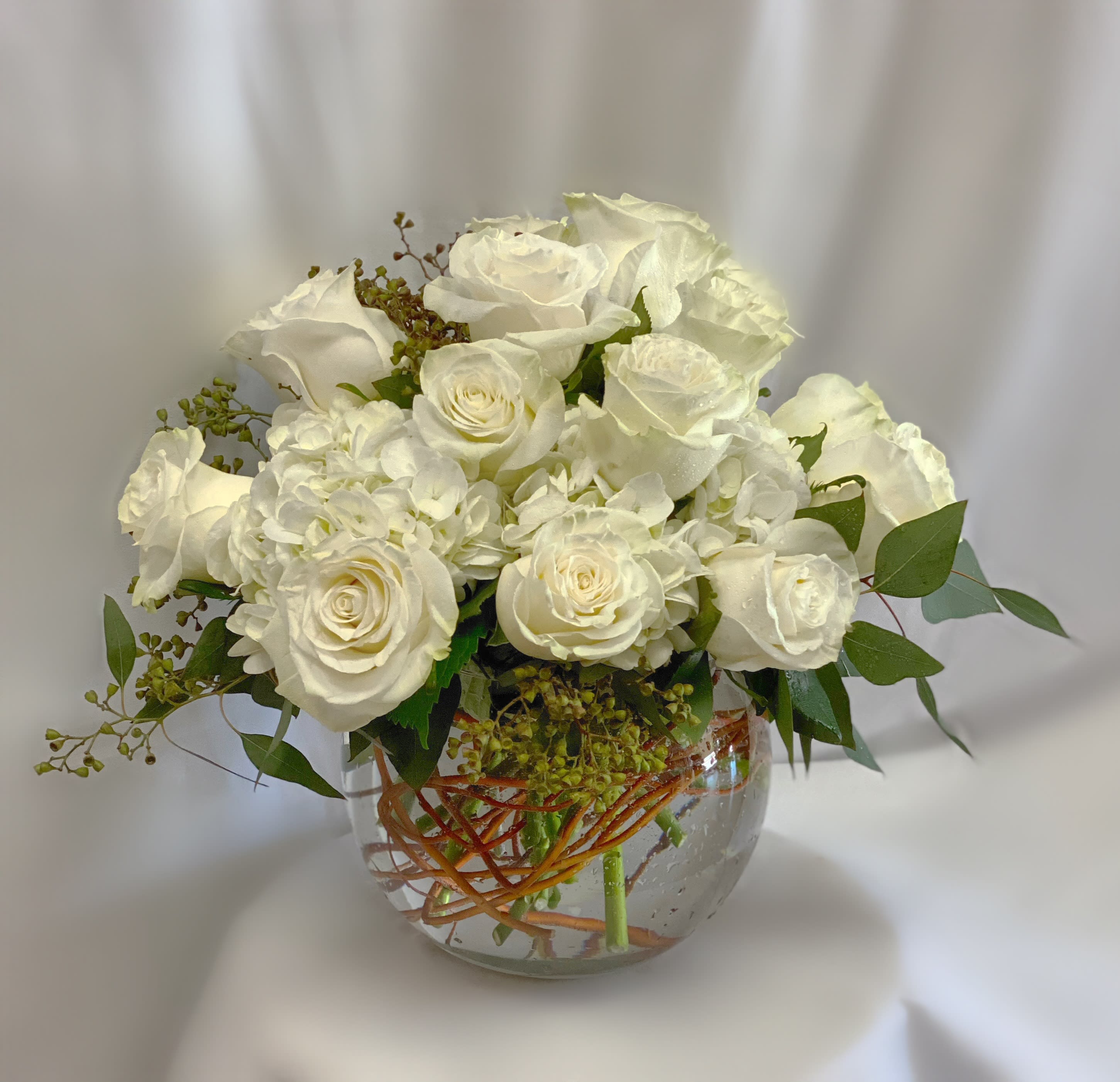 White roses and hydrangeas arranged in a clear glass vase