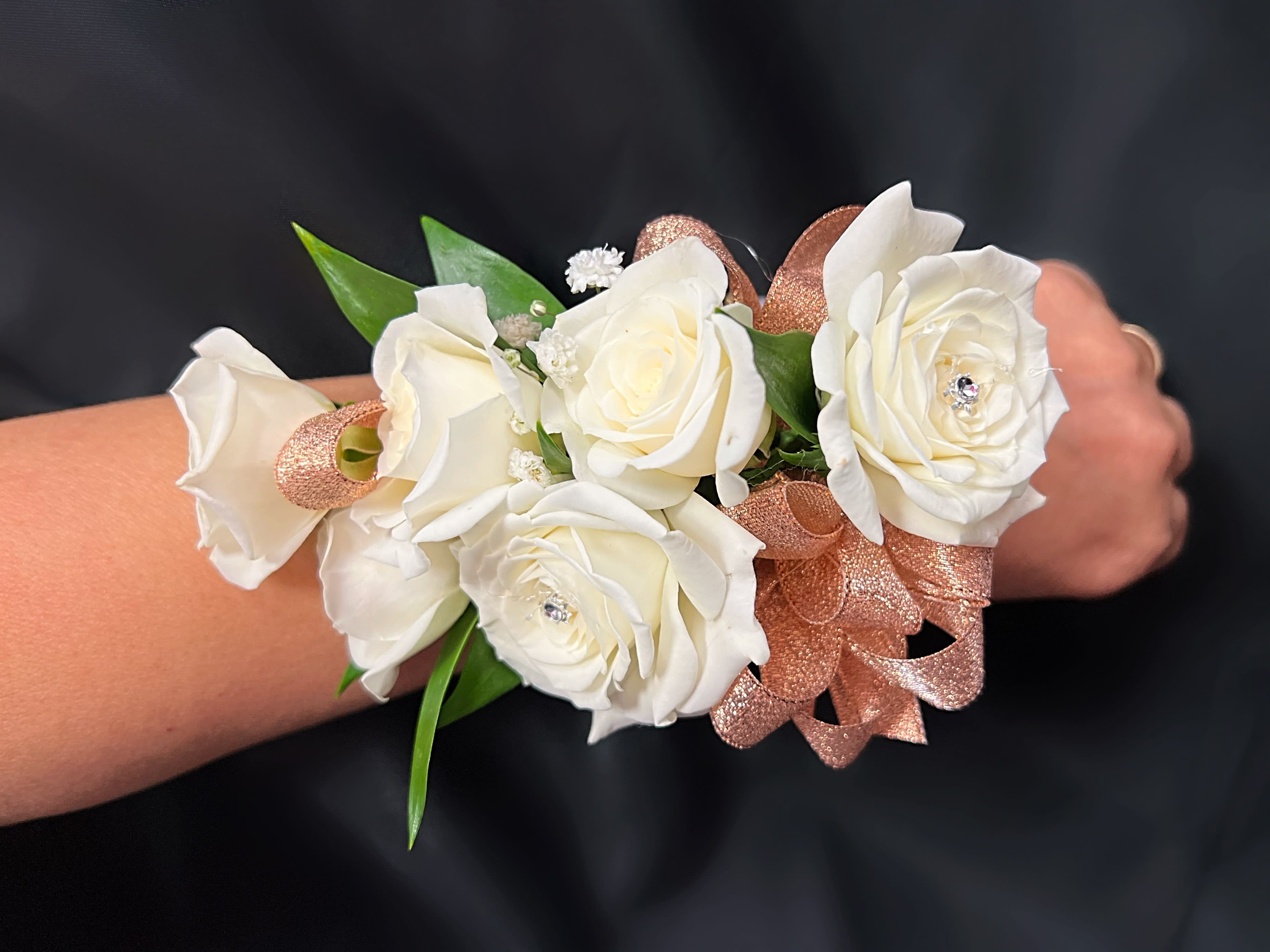 White rose wrist corsage with rose-gold ribbon on a wrist