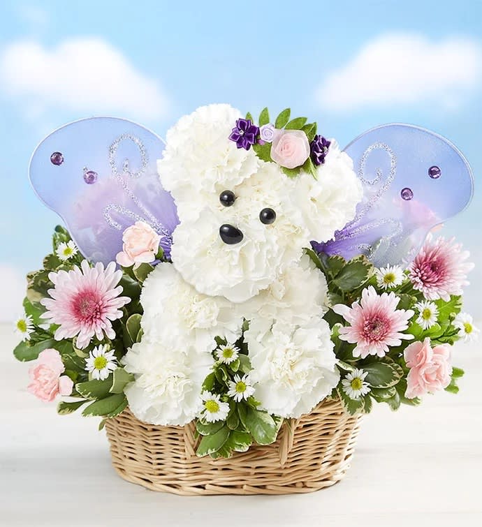 White teddy bear floral arrangement in a wicker basket with purple wings