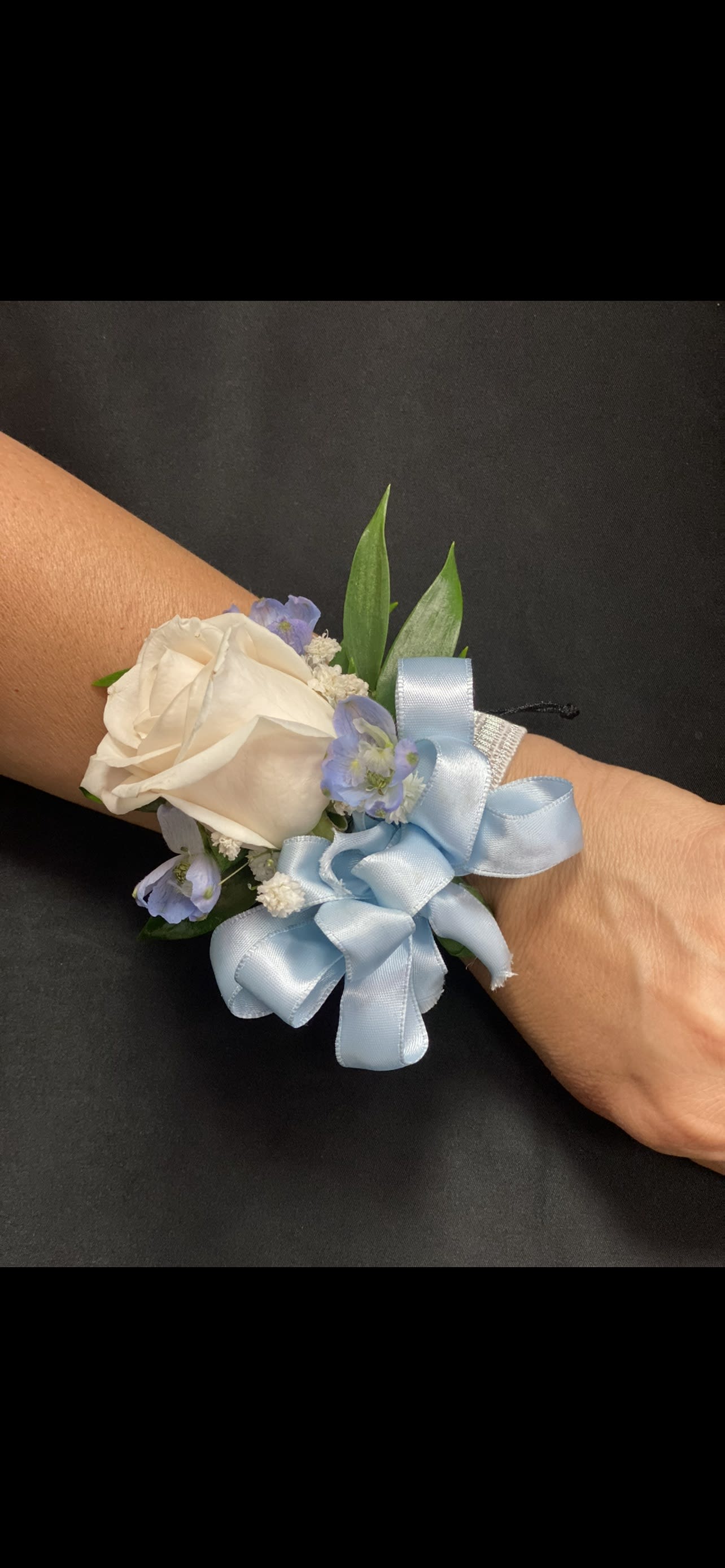 White rose wrist corsage with pale blue ribbon and small blue flowers