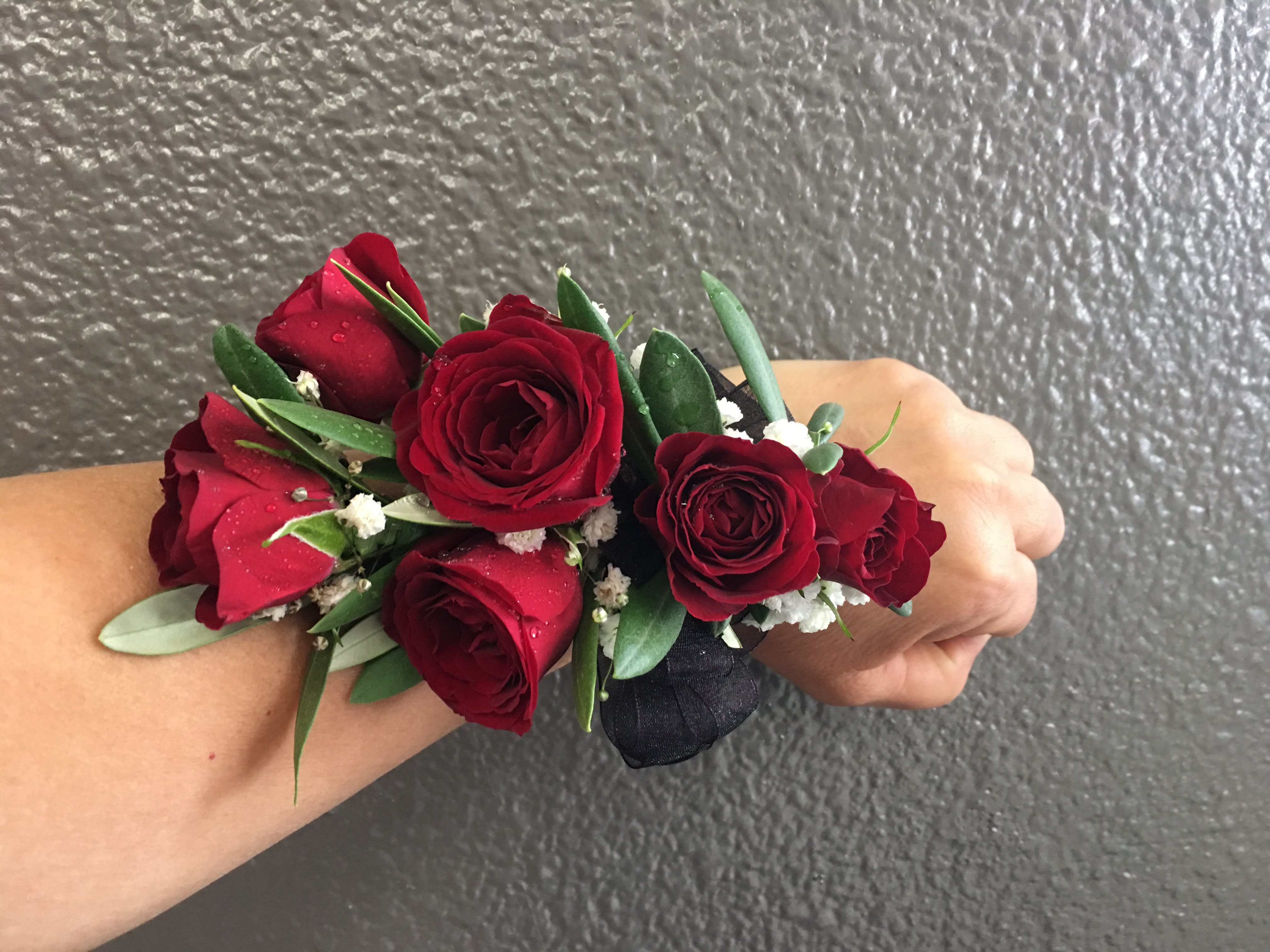 Red rose wrist corsage with greenery and white filler flowers