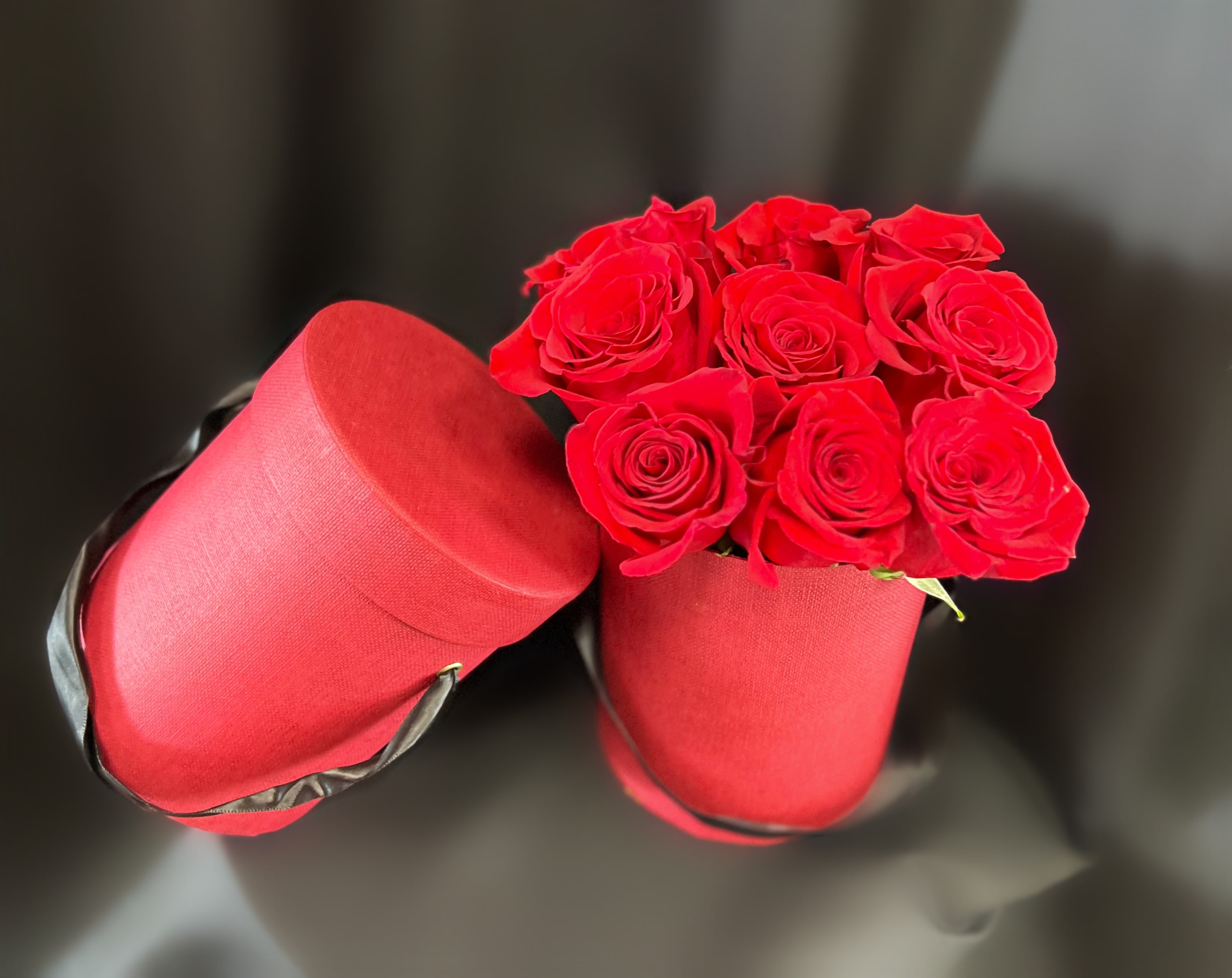 Red roses in two red hat boxes on a dark background