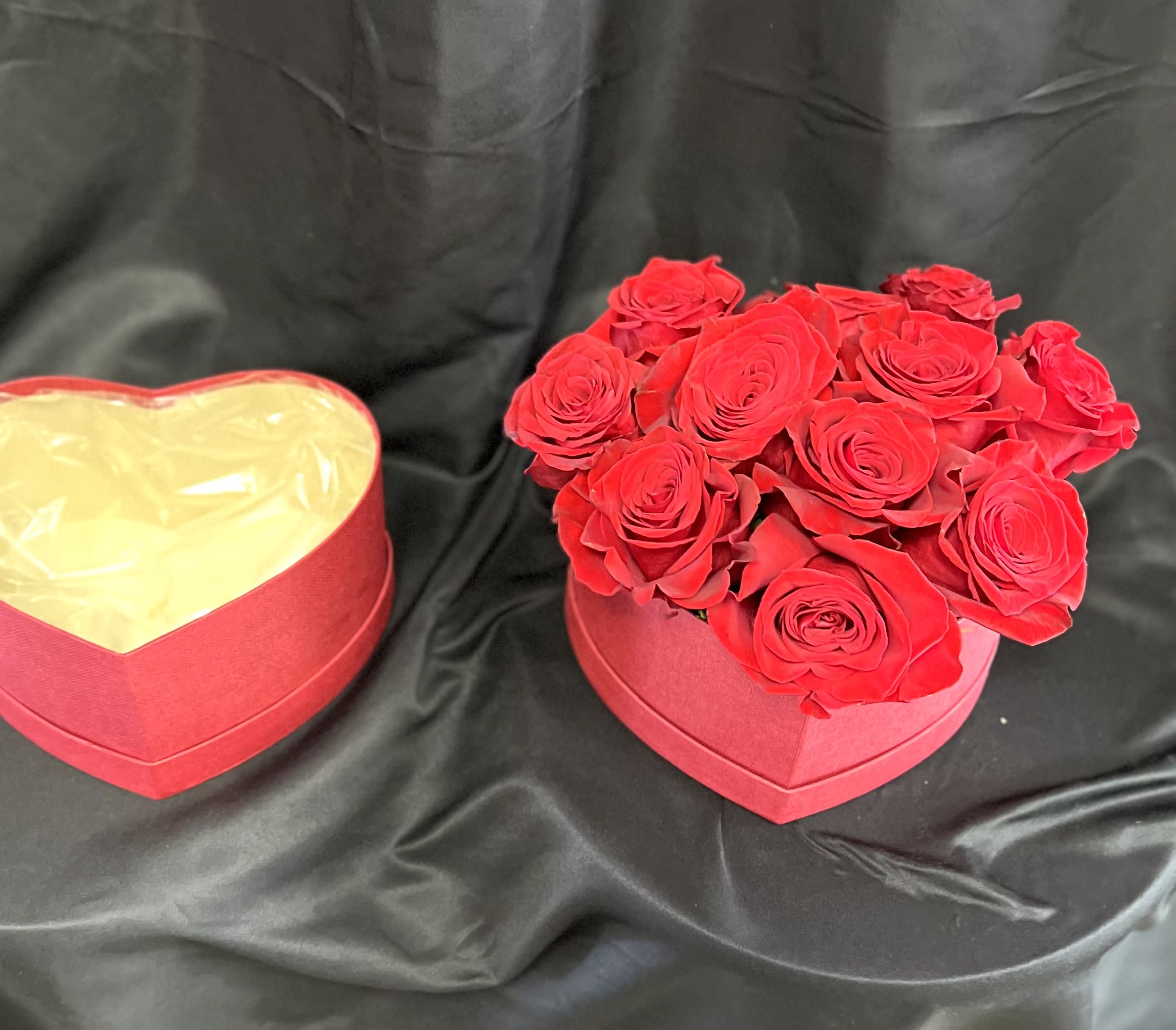Red roses in a heart-shaped box beside an empty matching box